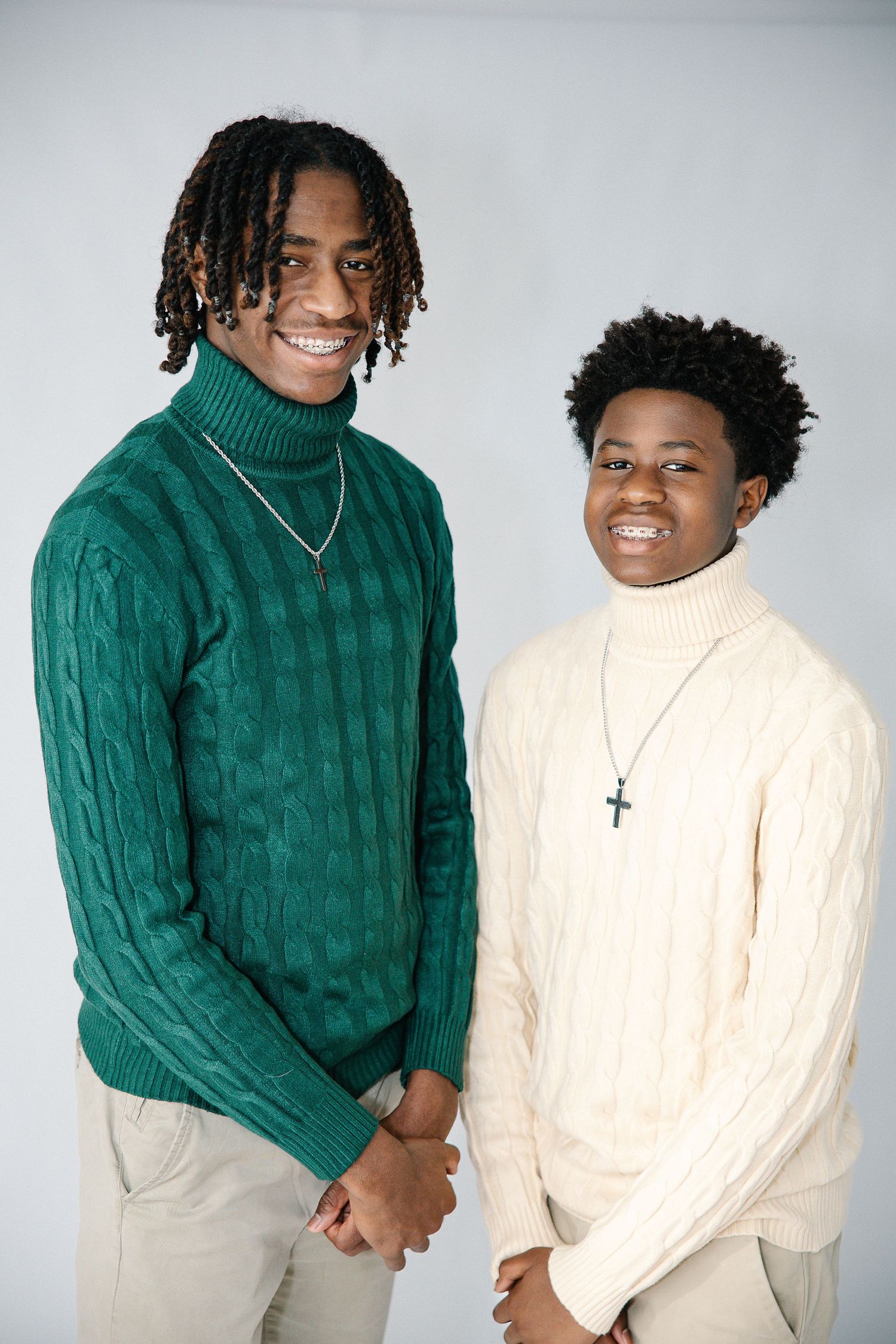 Two people in coordinating green and cream turtleneck sweaters smile together.
