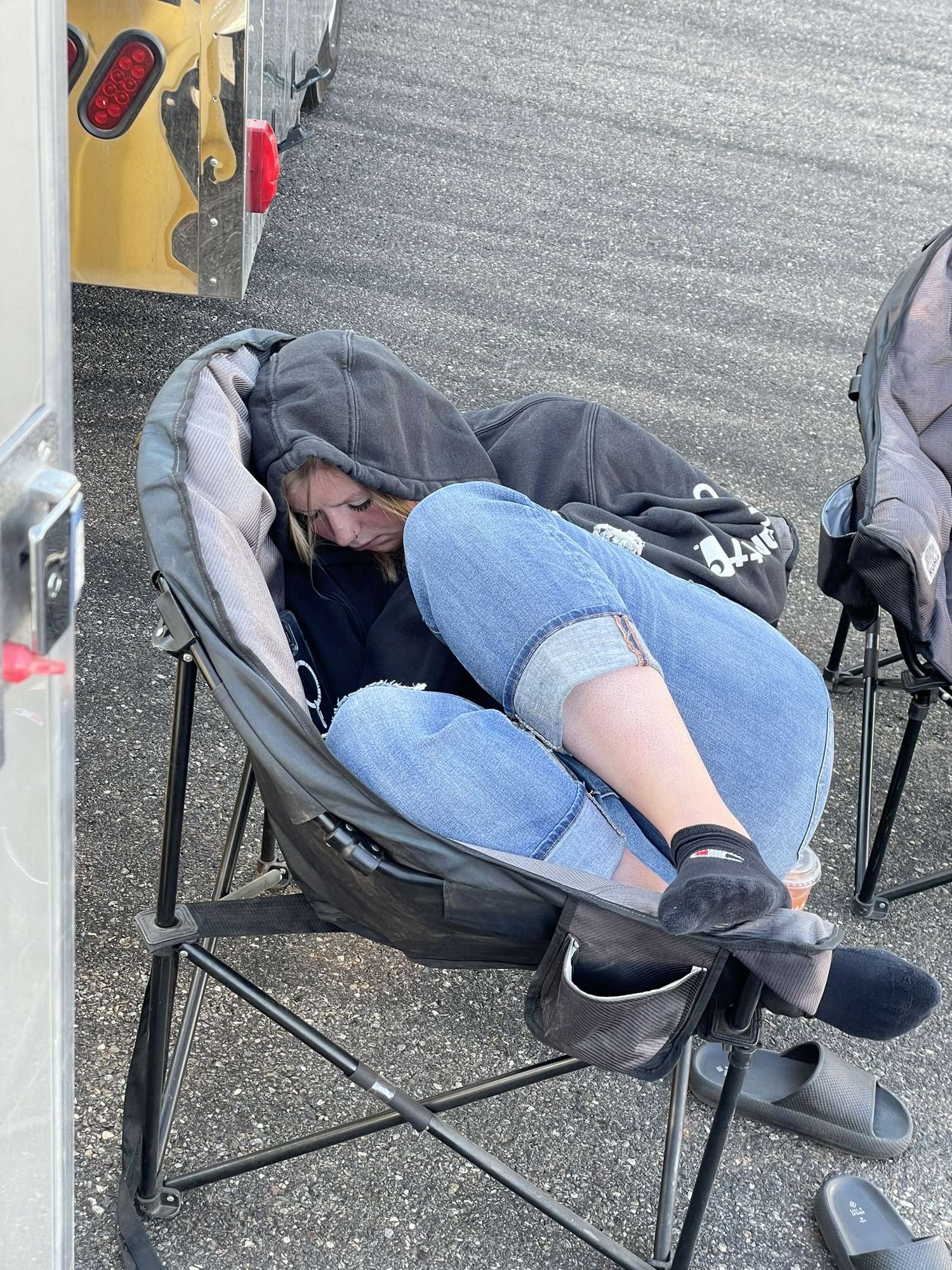 Becky napping hard in a fold-up chair at the track — photographer recharging after a long day of shooting.