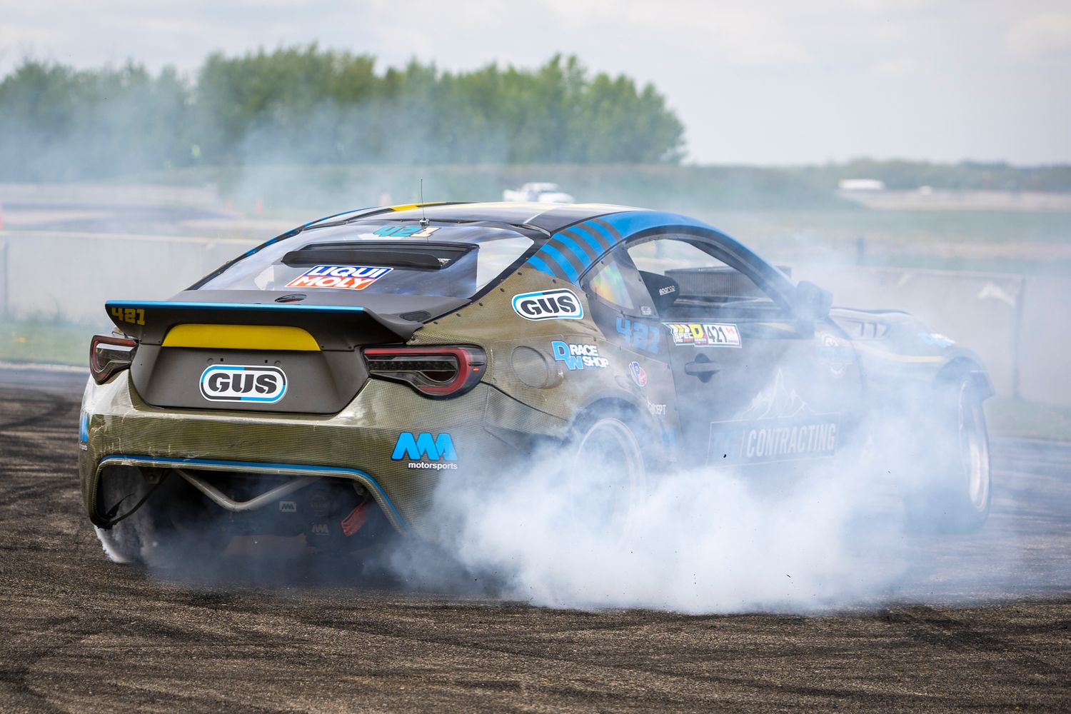 Camouflage-liveried drift car shreds tires and kicks up smoke mid-drift at Rad Torque Raceway during Spec D.
