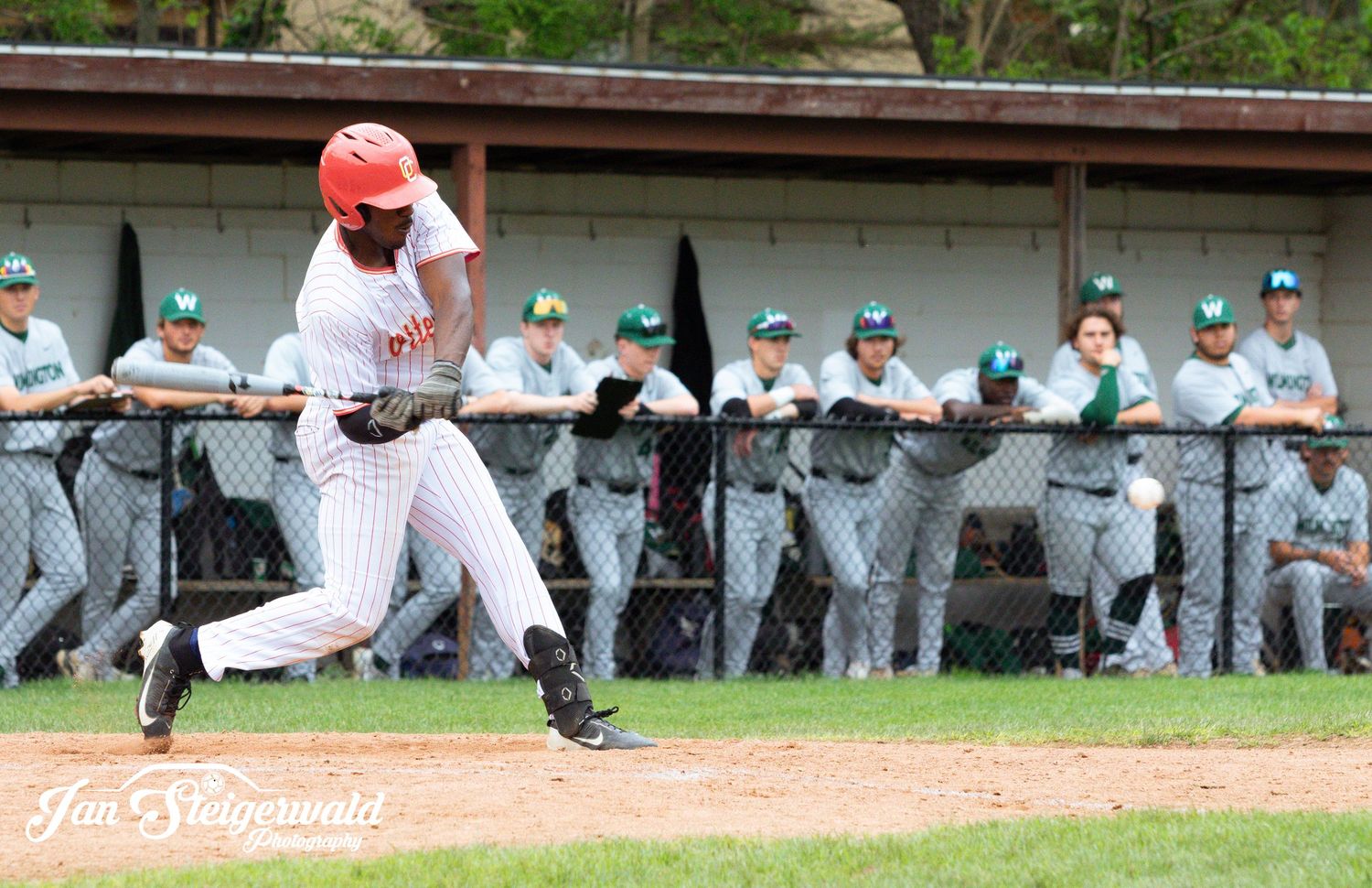 A baseball player in white uniform sliding into base during an intense game while fielders attempt to make the play.