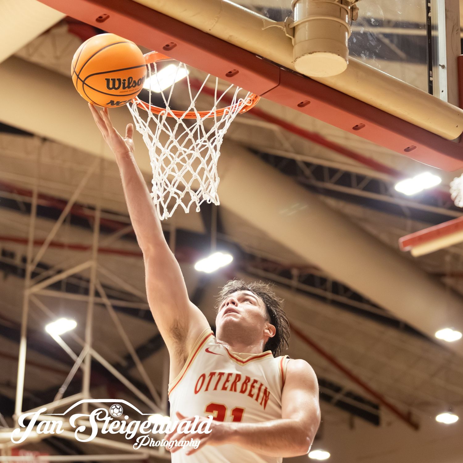 Basketball player soars through the air attempting a layup during an intense indoor game.
