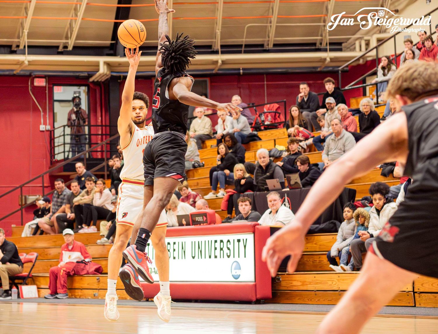 A university basketball game showing players battling for position under the hoop during a competitive play.