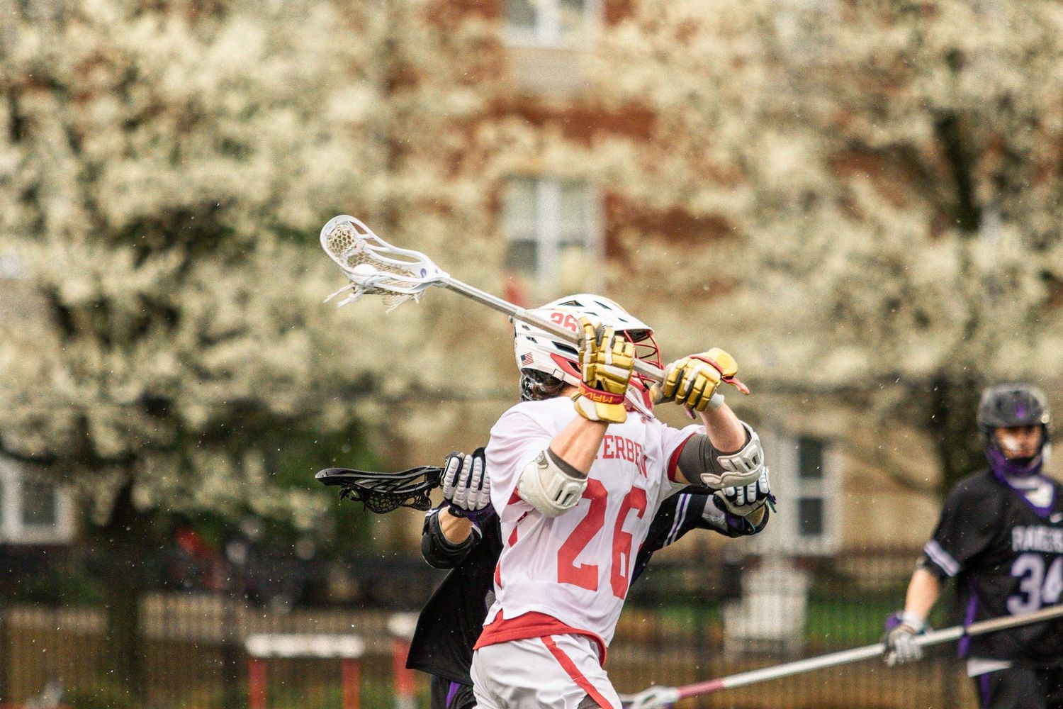 Lacrosse player in white uniform with number 20 taking a shot during outdoor game.