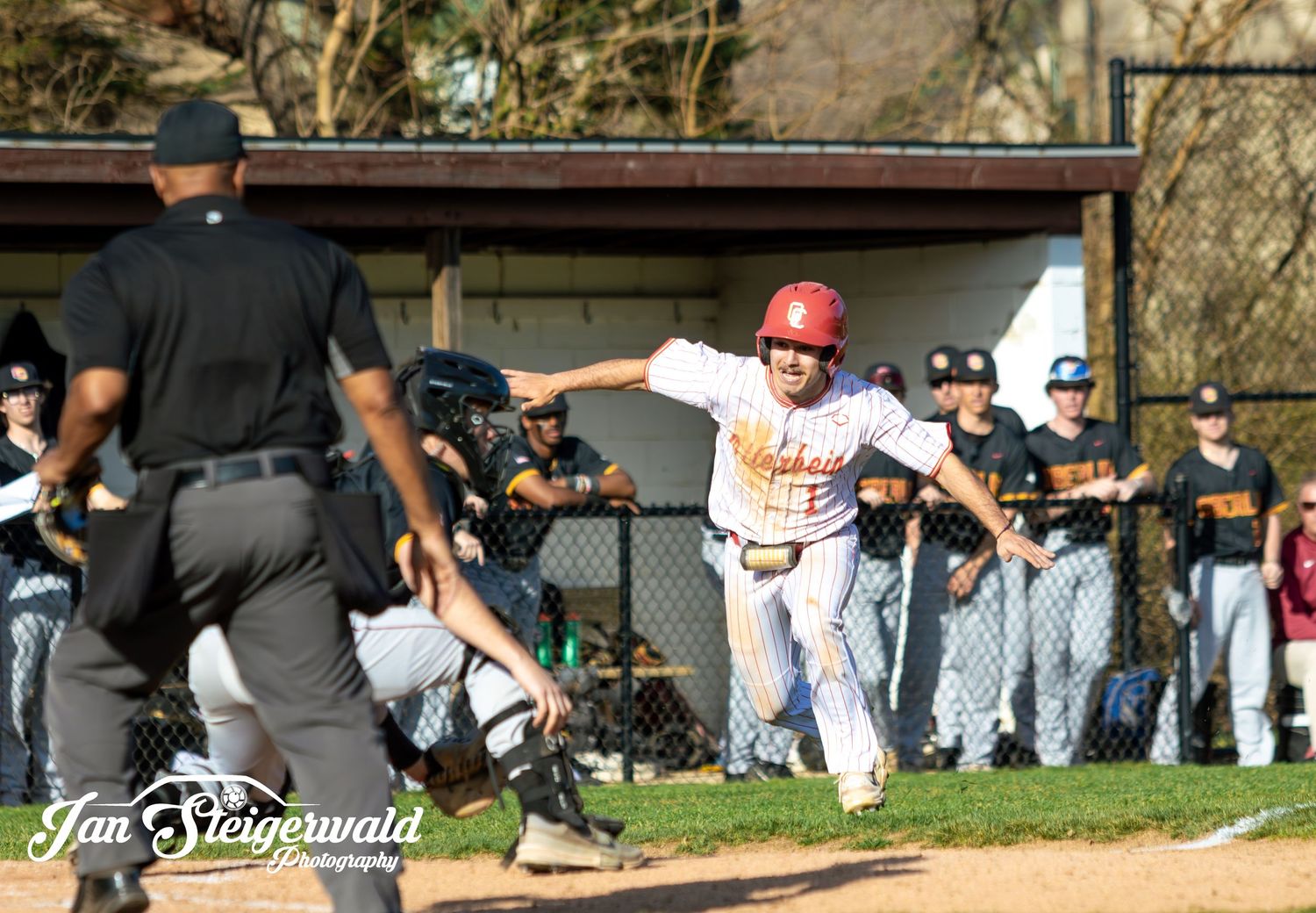 A baseball scene at home plate during a game with a player sliding and umpire watching the action.