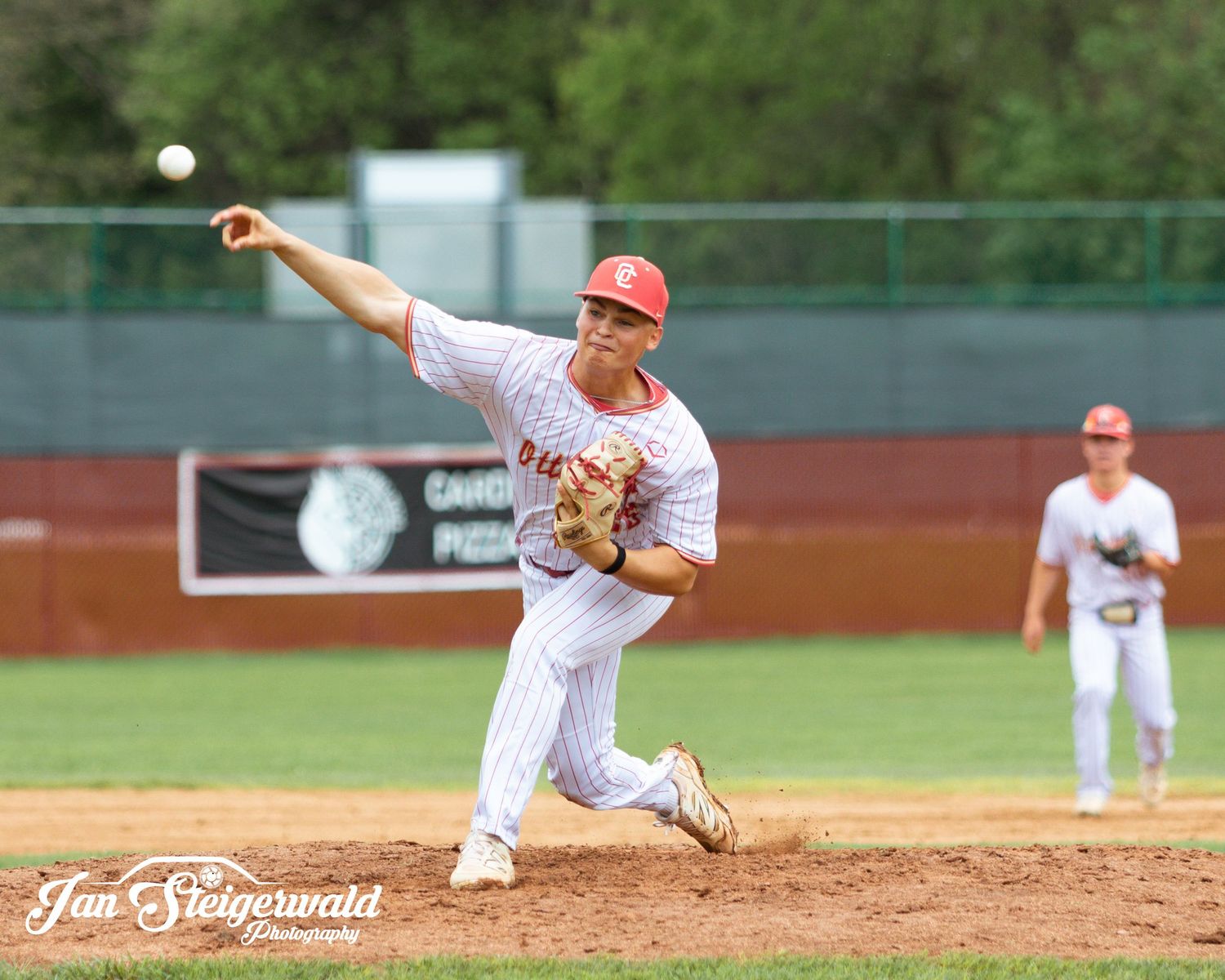 Baseball pitcher in mid-delivery motion releases ball from mound during game action.