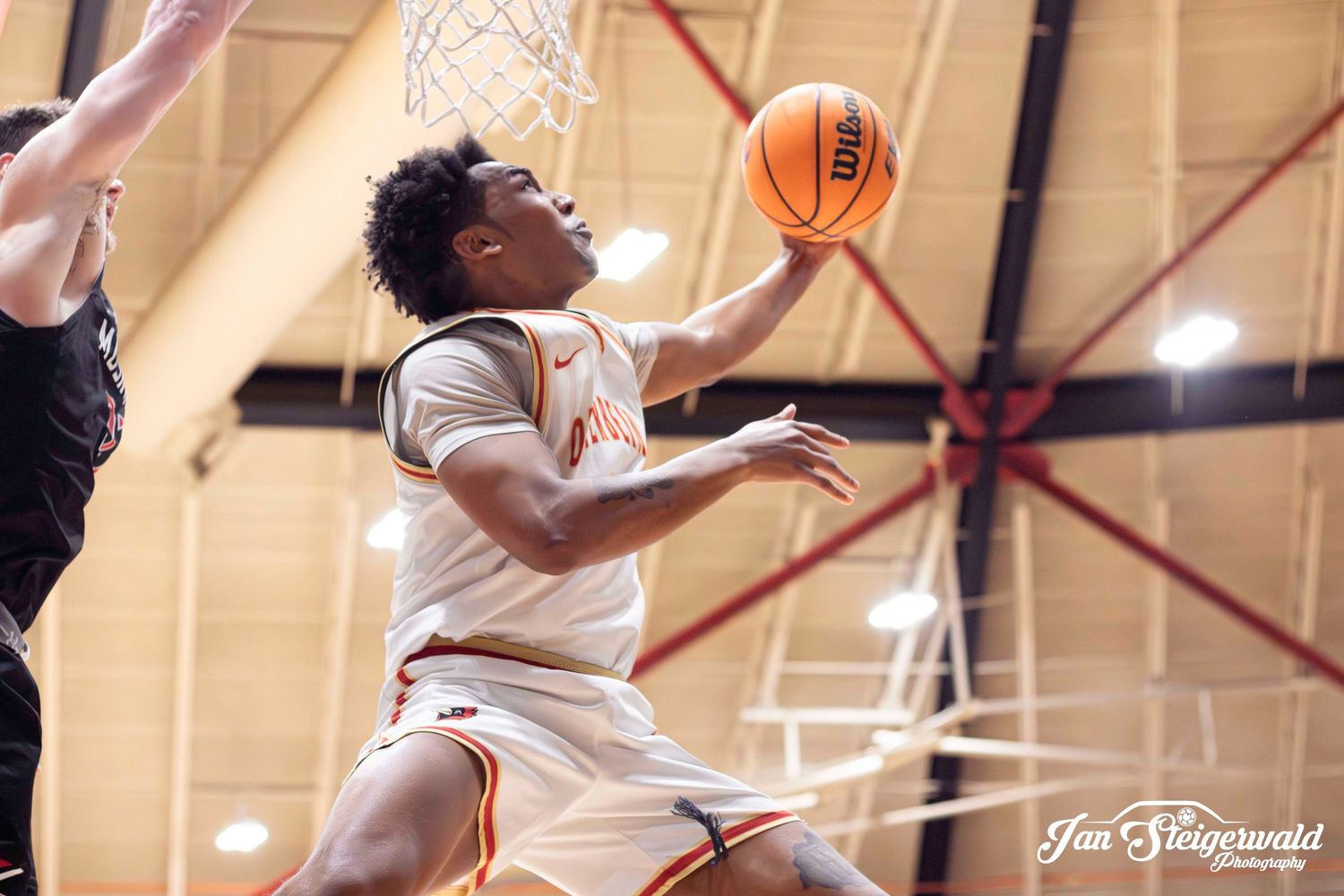 Basketball players in white uniforms compete during an intense indoor game showing various action shots on the court.