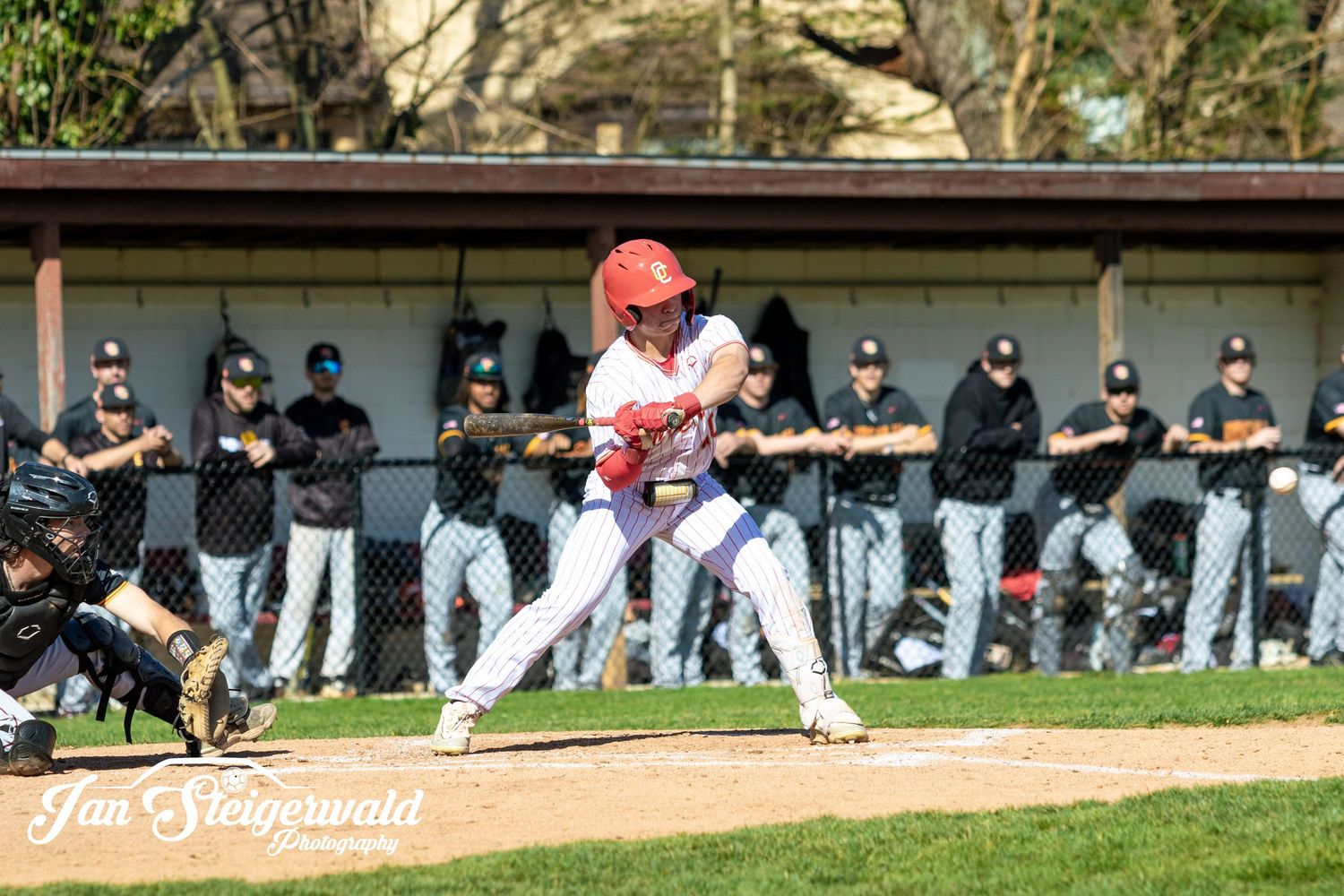 Baseball player in red helmet sliding into base during competitive game while fielder attempts to make the play.