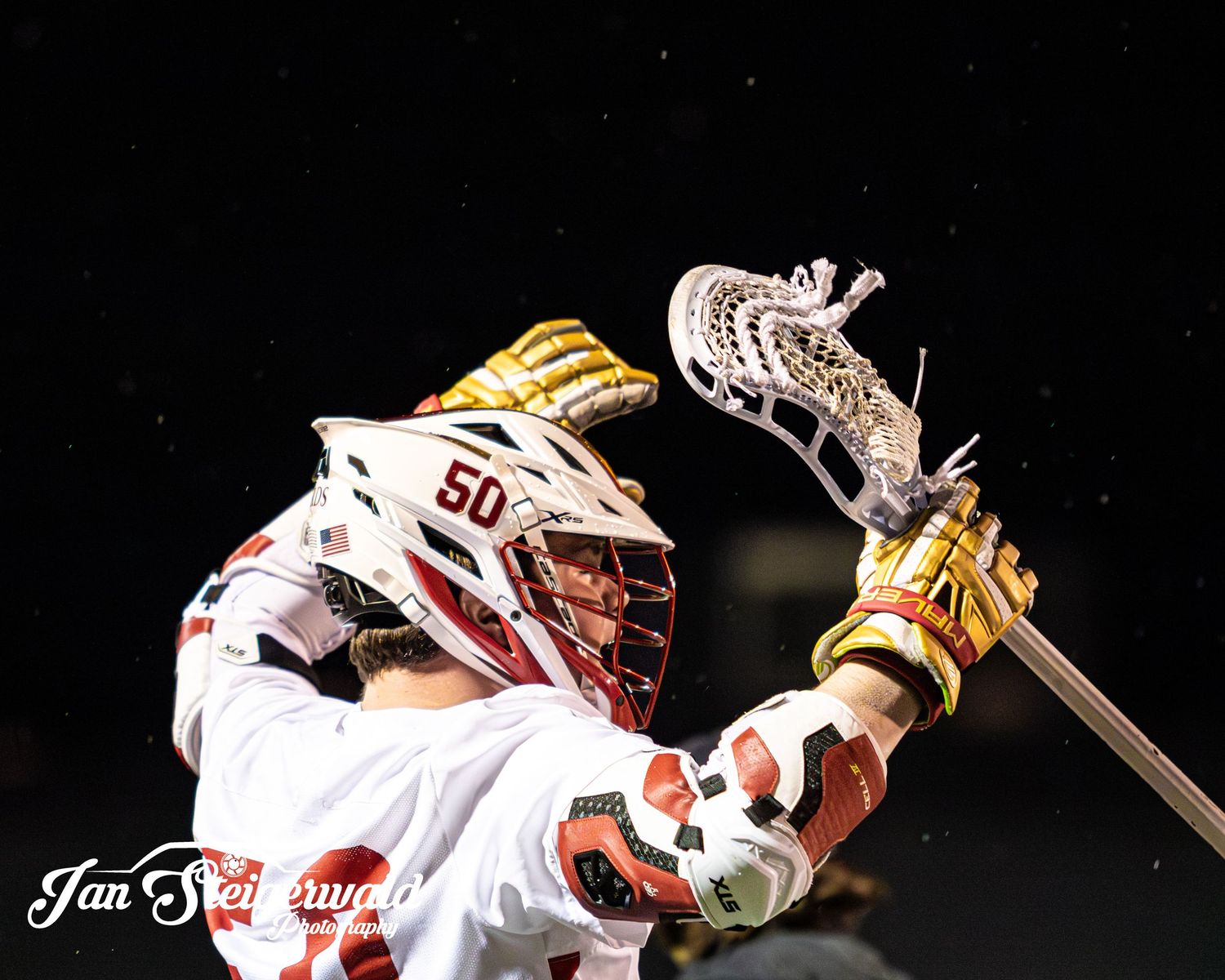 Goalie in white jersey and protective mask makes a glove save during an ice hockey game.
