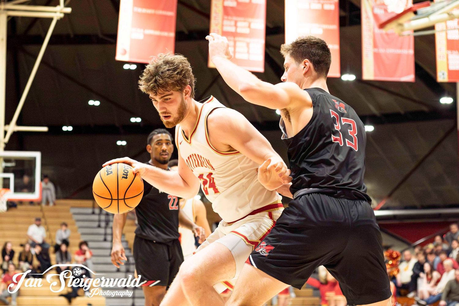Basketball players battle for possession during an intense game at an indoor sports arena.