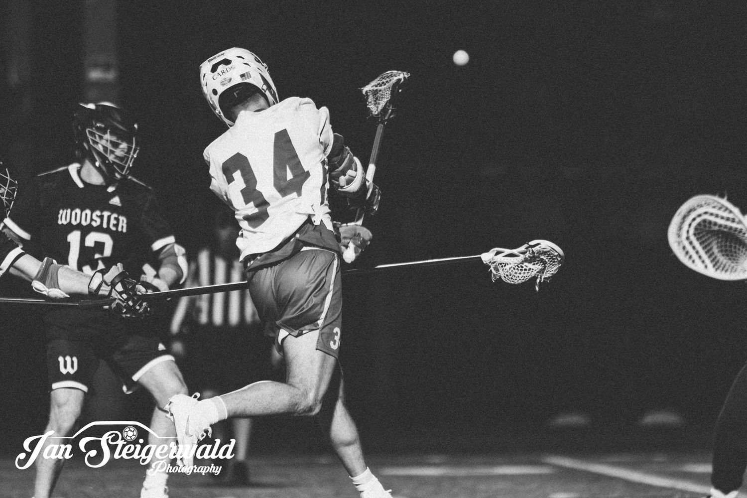Black and white photo of lacrosse players in action during a game, with number 34 prominently featured.
