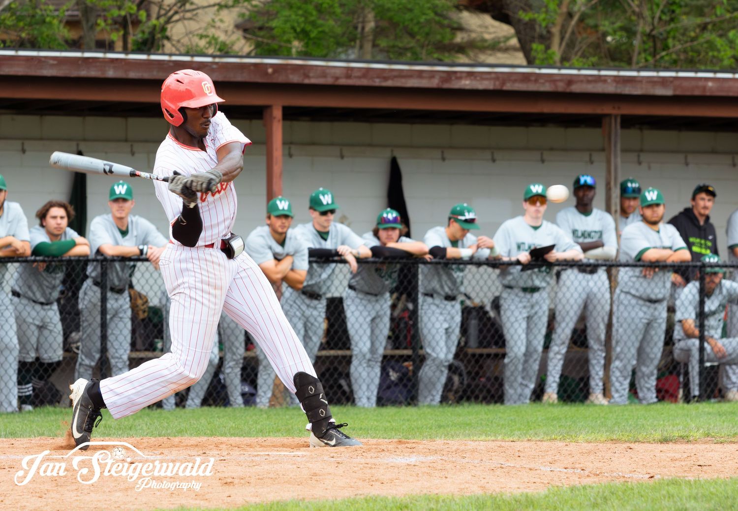 Baseball player slides headfirst into home plate during an intense game while teammates watch from the dugout.