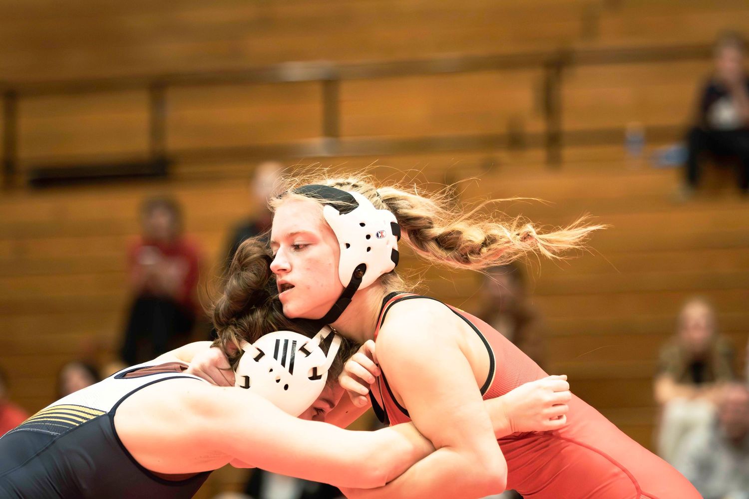 Intense wrestling match between two competitors in headgear during tournament.