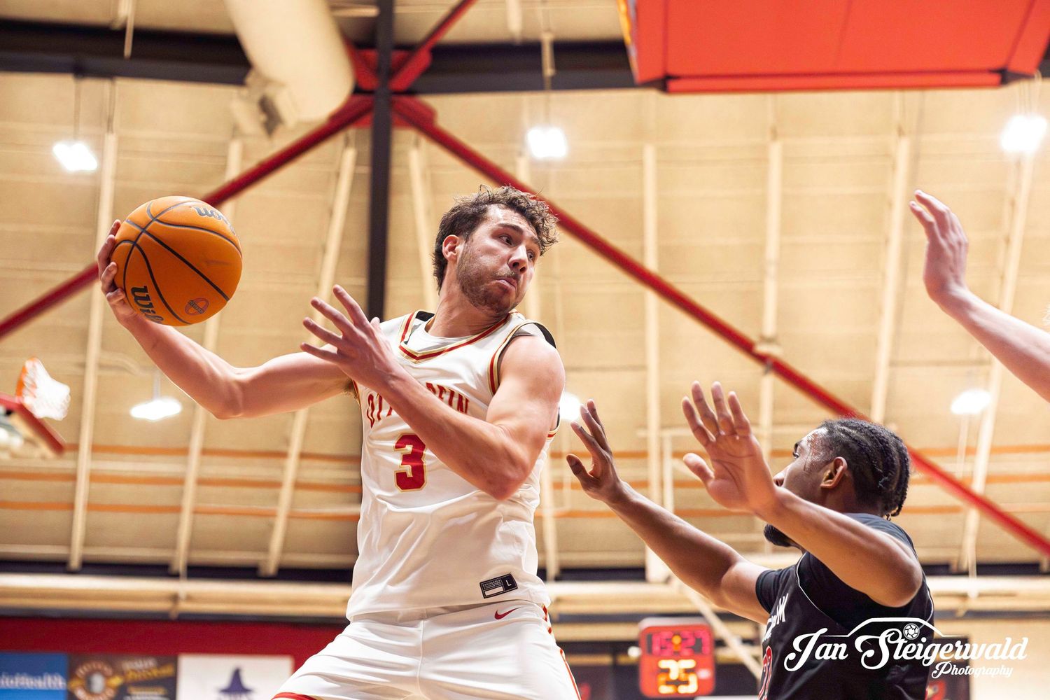 A point-blank basketball shot is captured during an intense indoor game in a gymnasium setting.