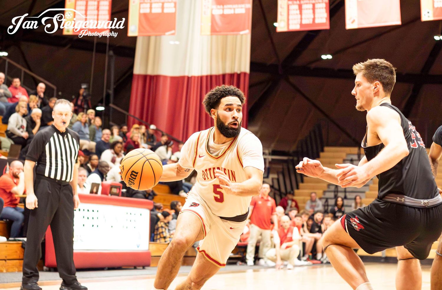 Players scramble for possession during a fast-paced college basketball game on the hardwood court.