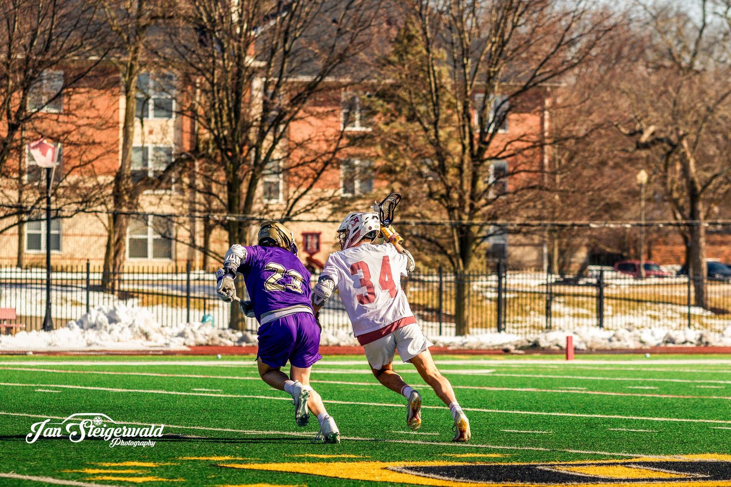 Soccer players compete for possession of the ball on a sunny spring day at an outdoor sports field.