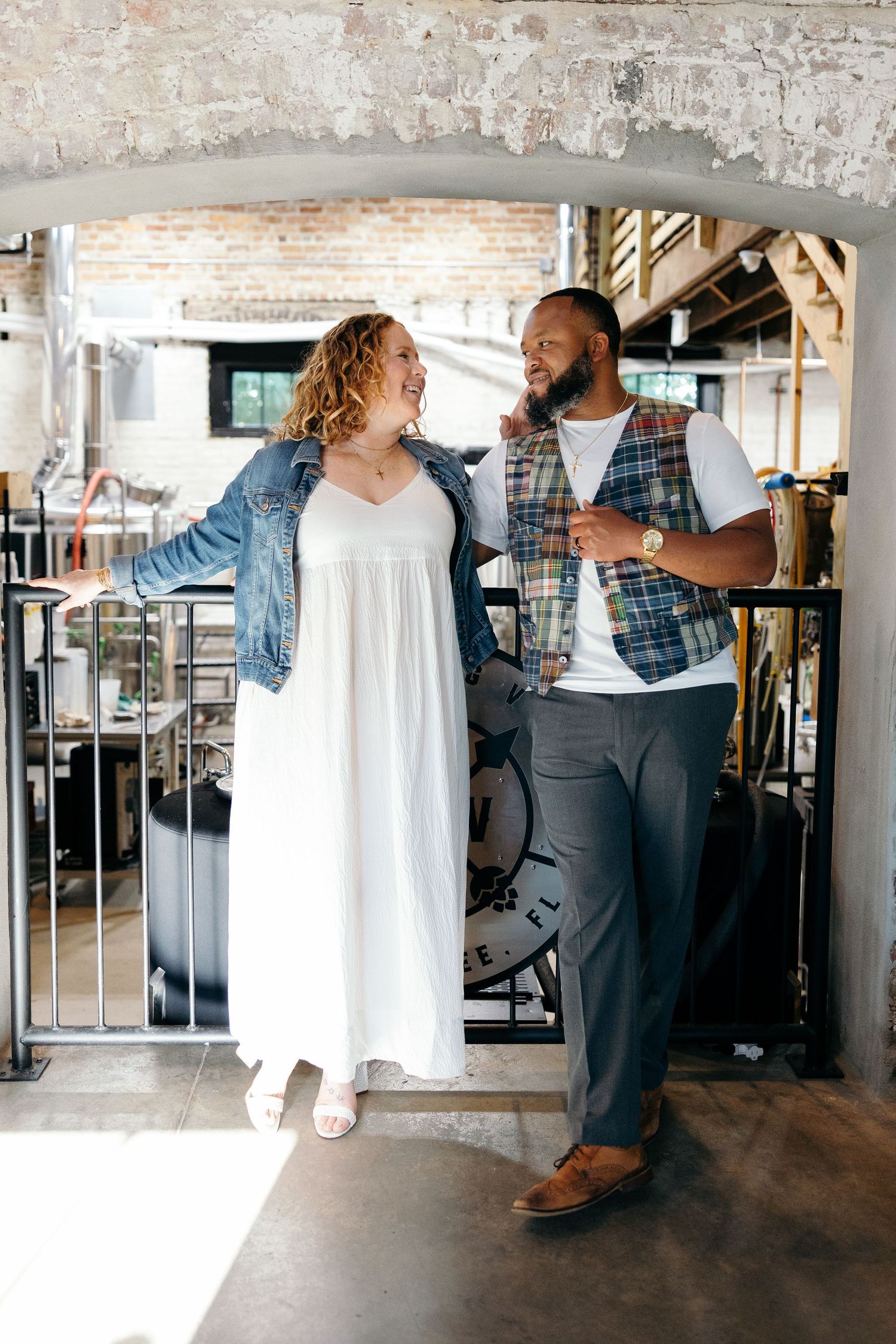 Couple in casual attire share a joyful moment together while standing in an industrial-style loft space.