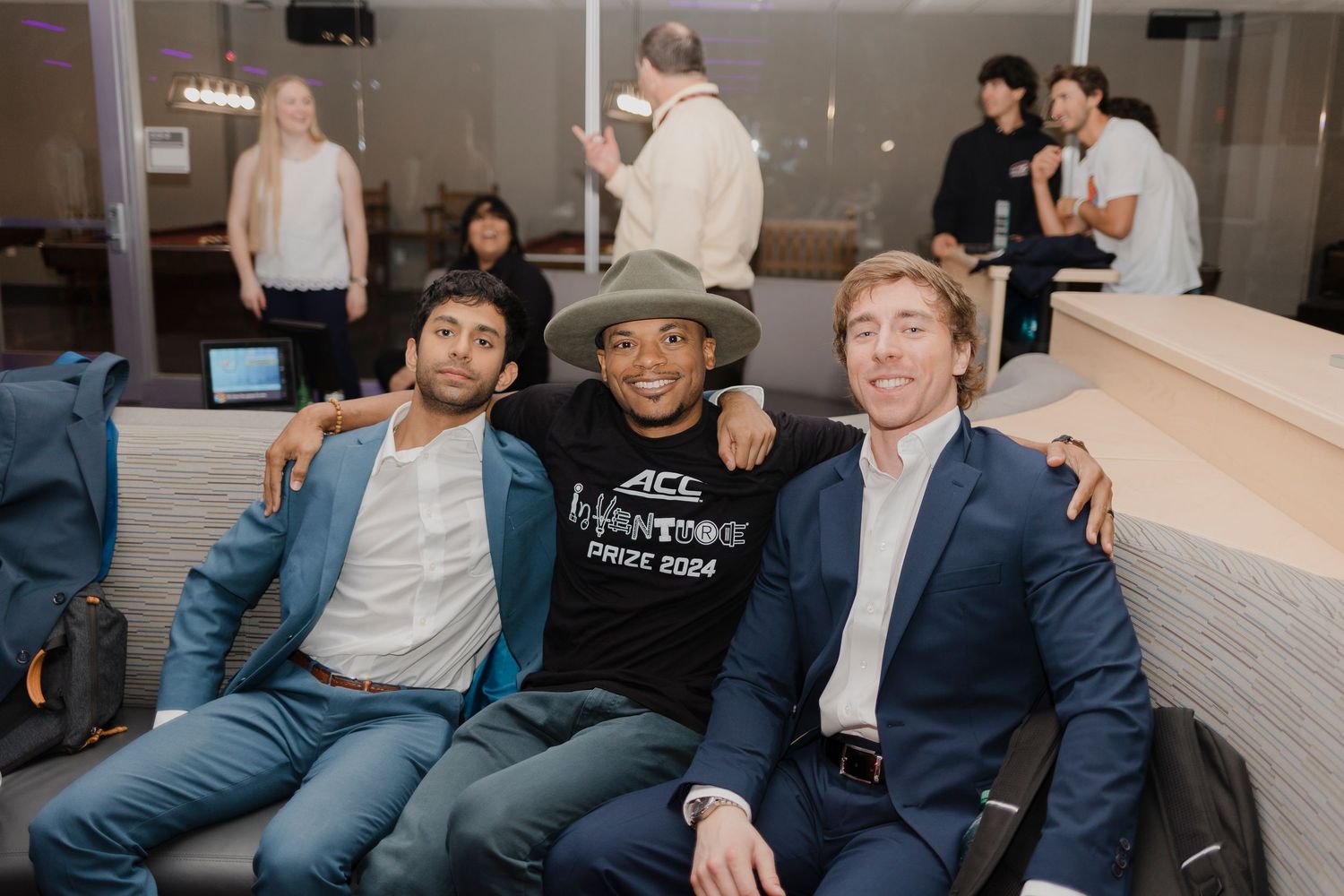 Three friends sit together on a couch in a bright indoor setting during a casual gathering.