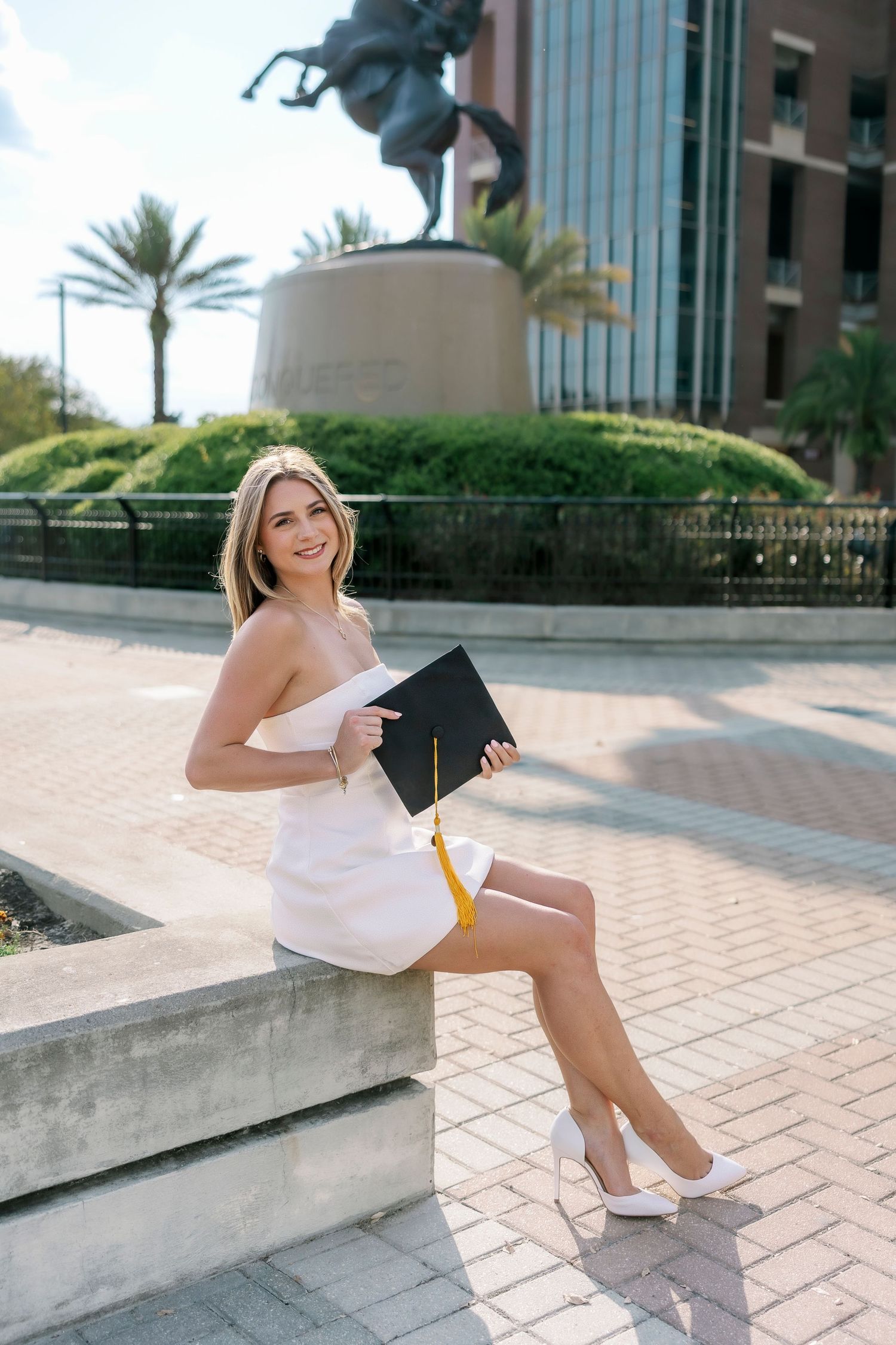 Professional lifestyle photos of someone in casual white attire posing on outdoor concrete steps near modern buildings.