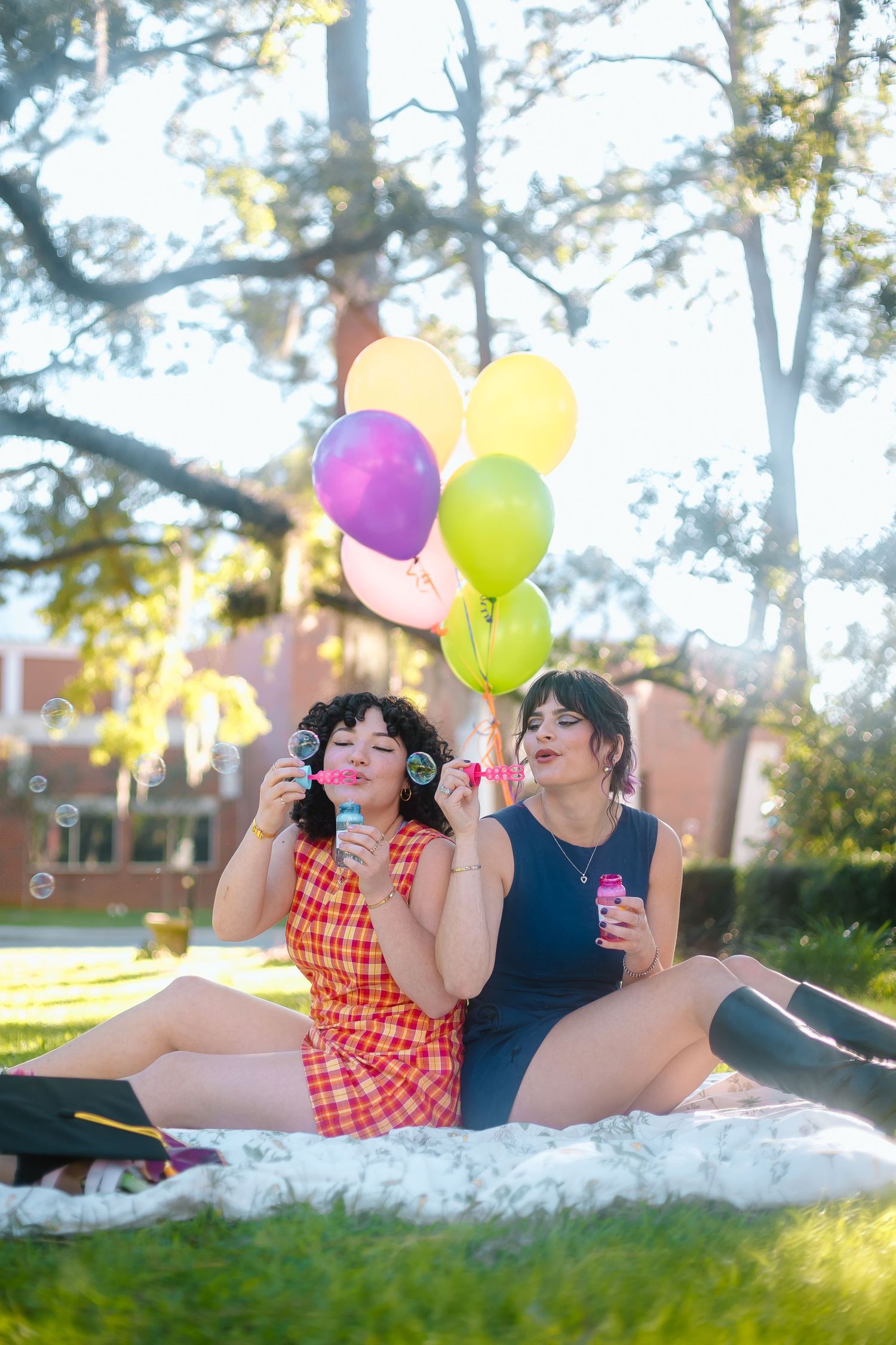 FSU Friends blow bubbles and hold colorful balloons during outdoor graduation photo session.