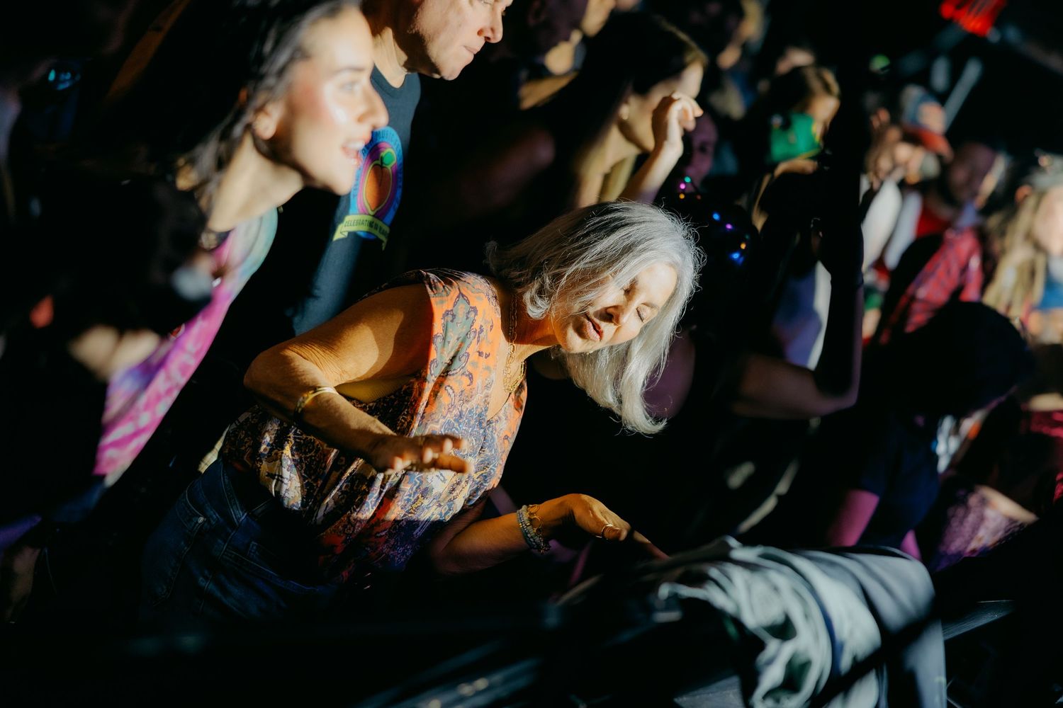 A crowd of people dancing and enjoying themselves at a nightclub or party with colorful lighting effects.