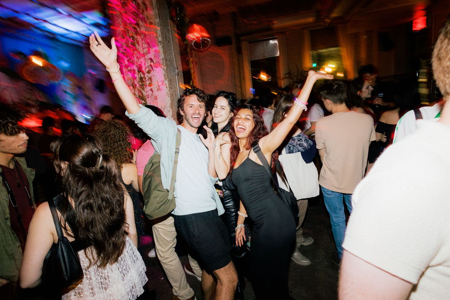 People dancing and celebrating at a lively indoor party with colorful lights and music.