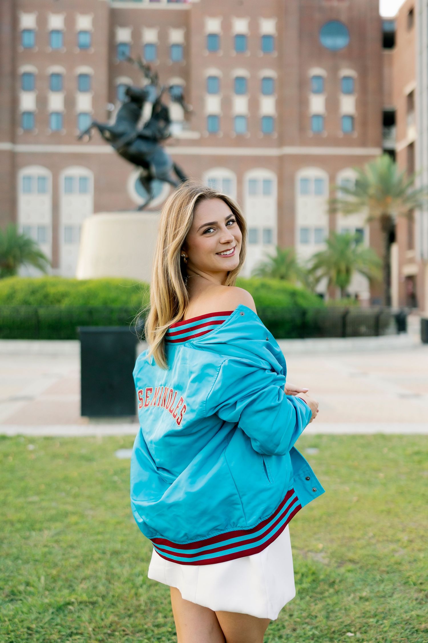 Person wearing a bright turquoise jacket poses outdoors against brick building backdrop in a series of photos.