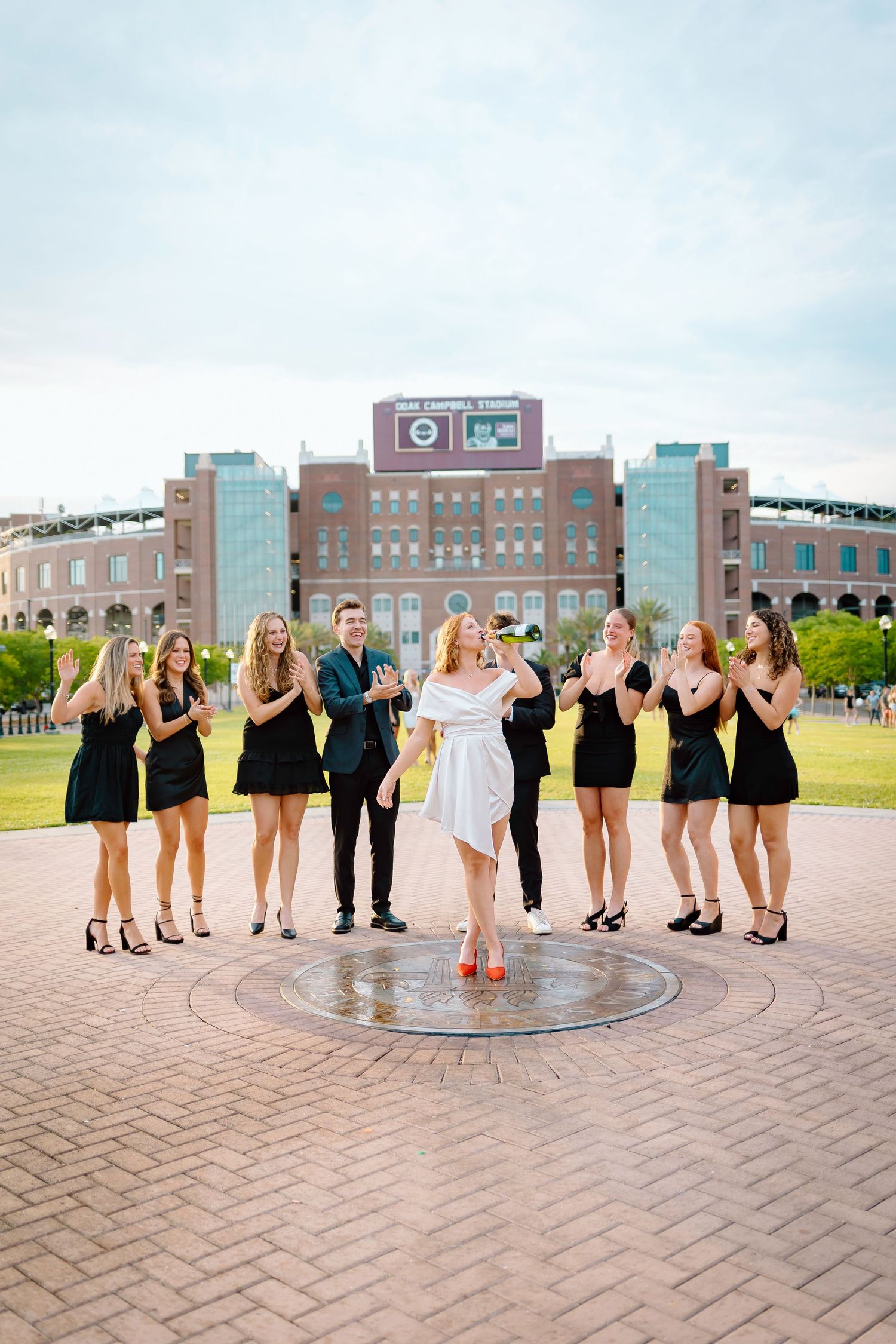 Wedding party poses in sequence on brick plaza with urban buildings in background.