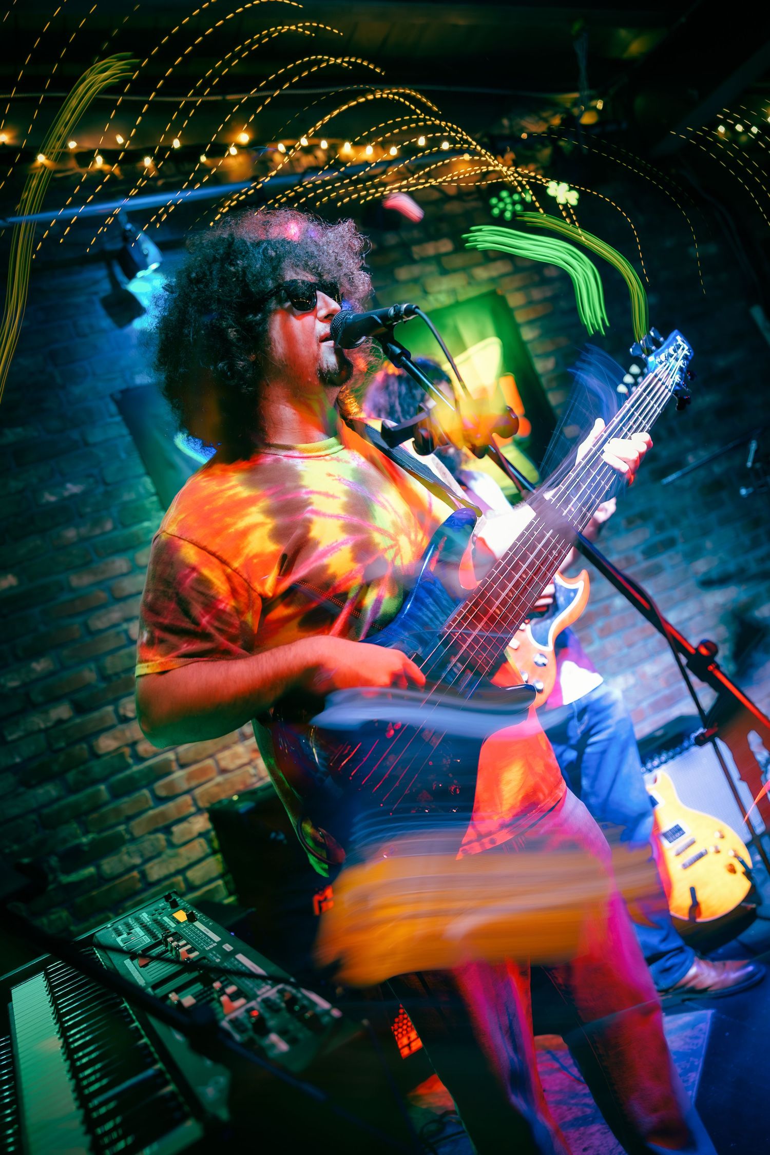 Motion blur captures guitarist performing energetically under colorful stage lights in a nightclub atmosphere.