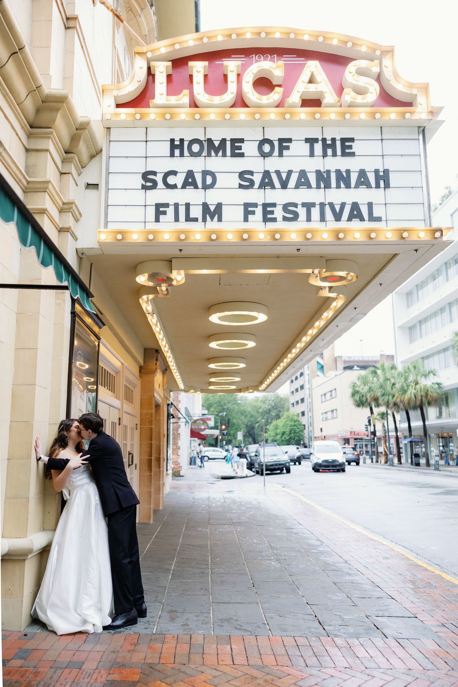 Bride and groom kissing under the Lucas Theatre marquee at SCAD Savannah Film Festival in Savannah, GA.