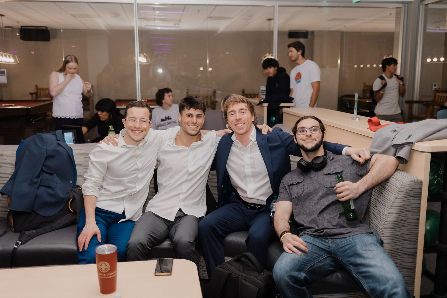 Coworkers gather together in a modern office space having casual conversations and interactions at their desks.