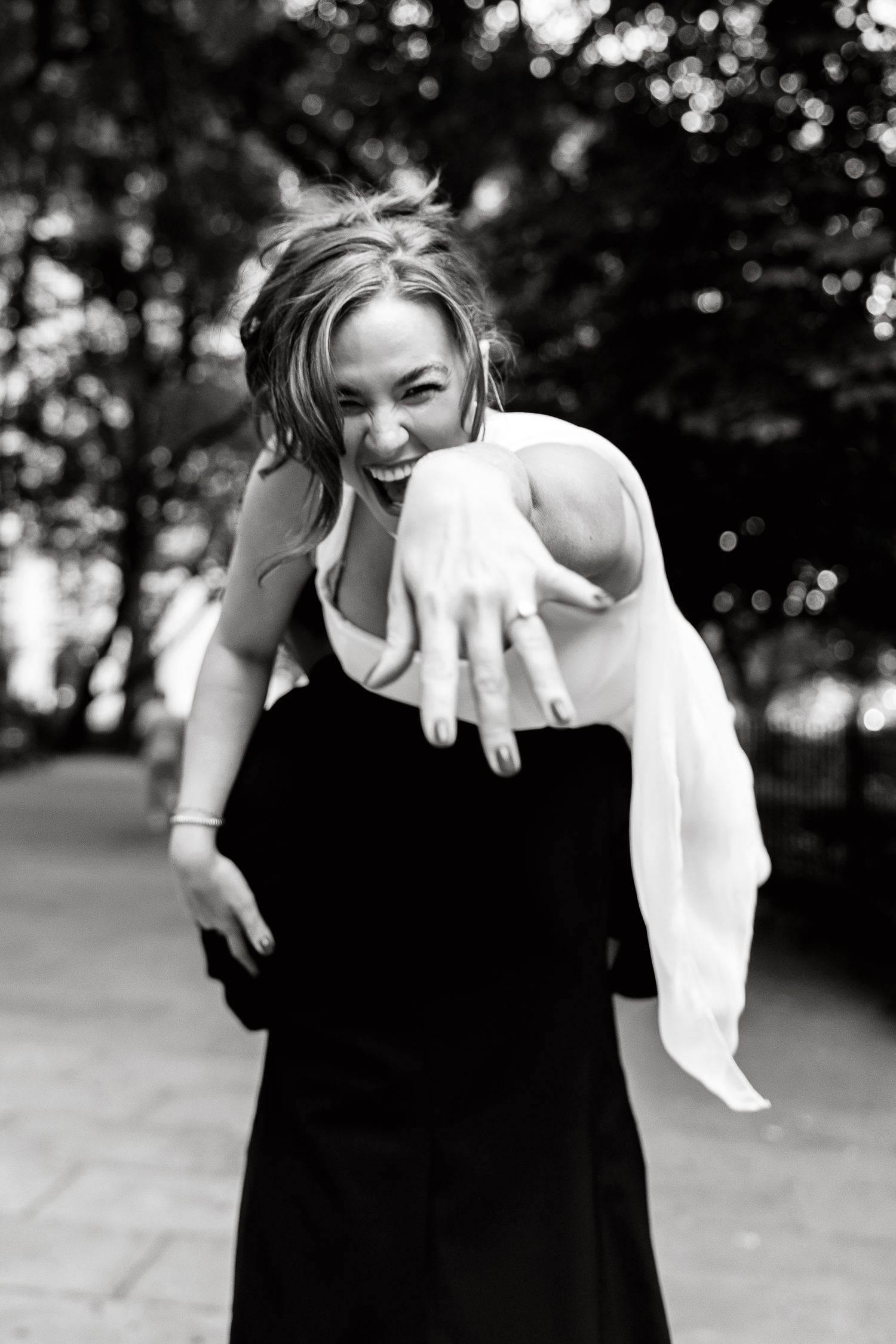 A black and white photo series shows a person in a black dress playing and interacting with a white cloth outdoors.