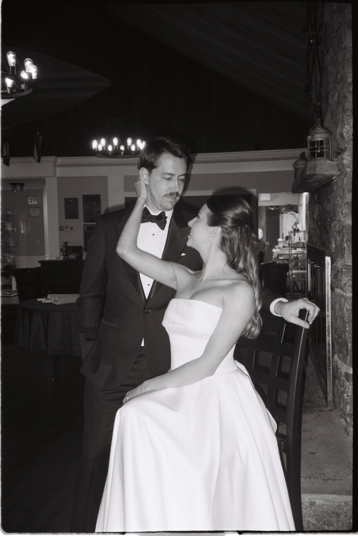 Bride and groom share an intimate first dance moment indoors in elegant black and white wedding photography.