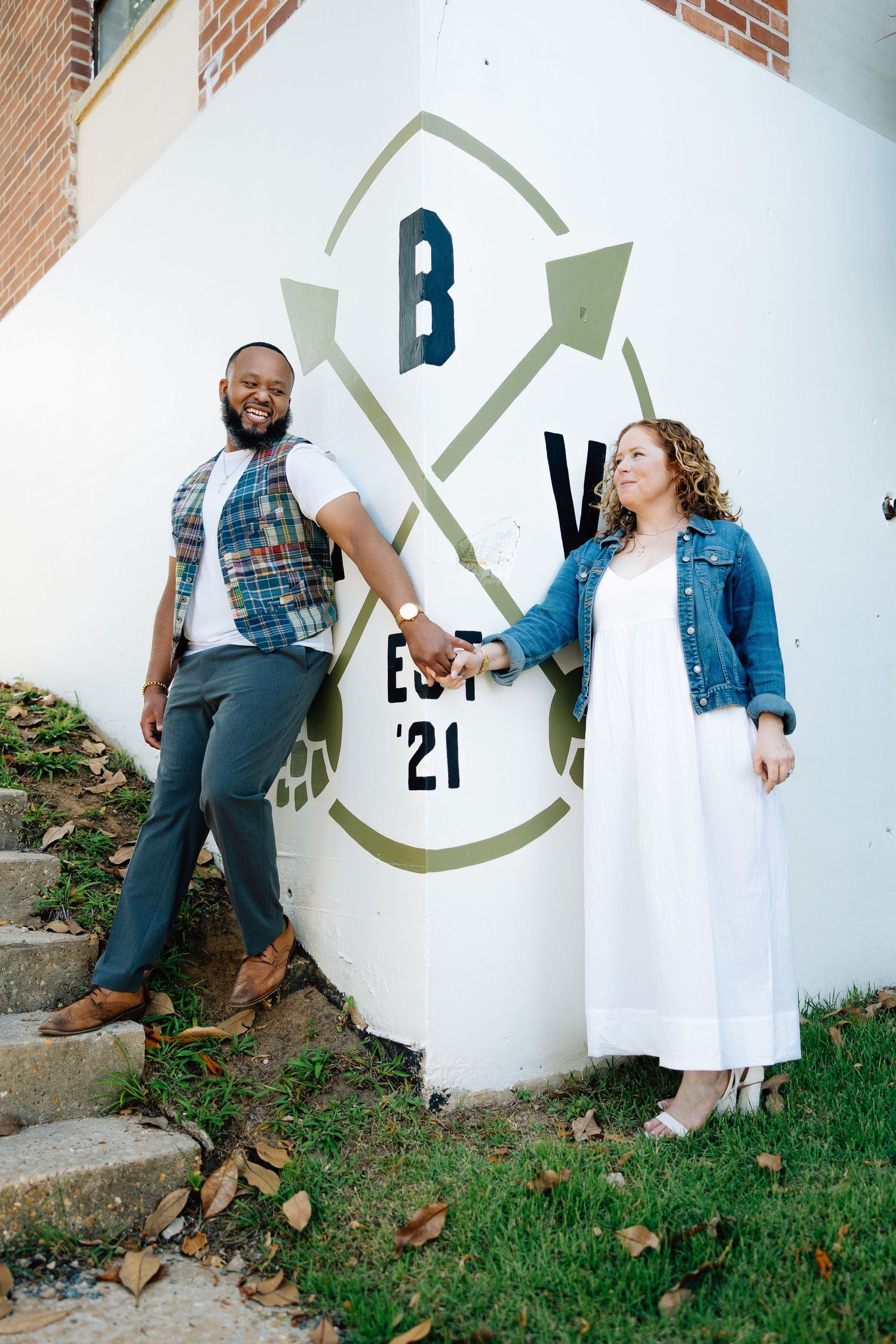 Five artistic engagement photos showing a couple posing against a white wall with a circular logo design outdoors.