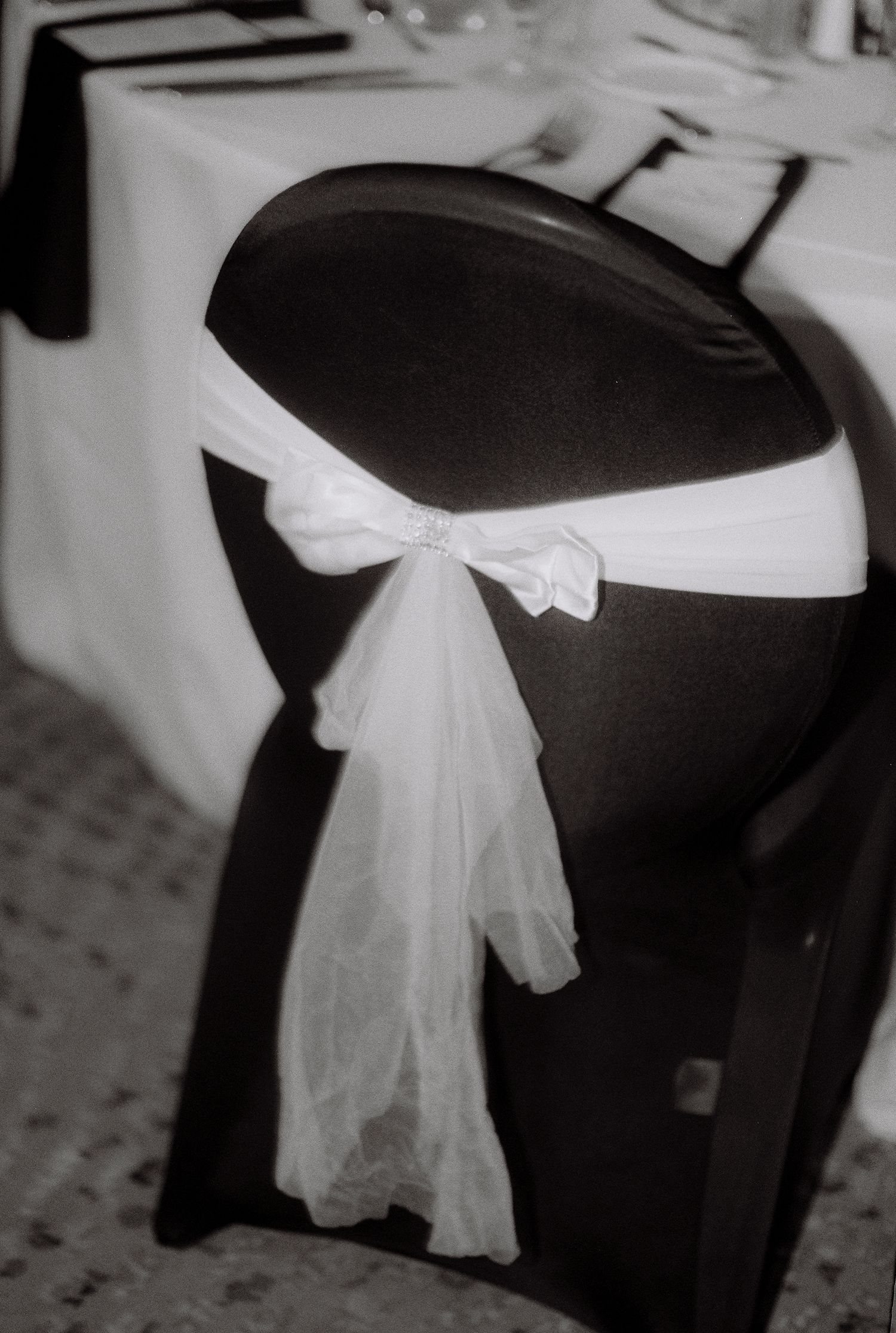 Black chair cover with elegant white tulle bow, perfect for wedding reception decor.
