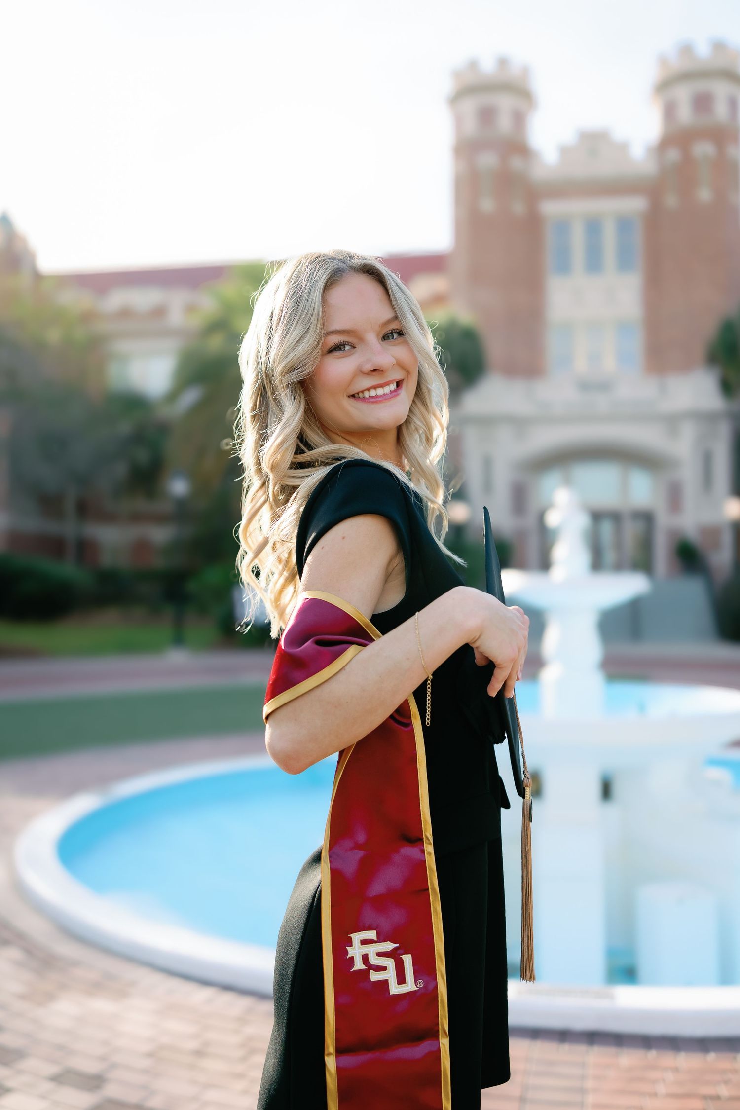 A series of graduation photos taken on a college campus with a fountain and brick buildings in the background.