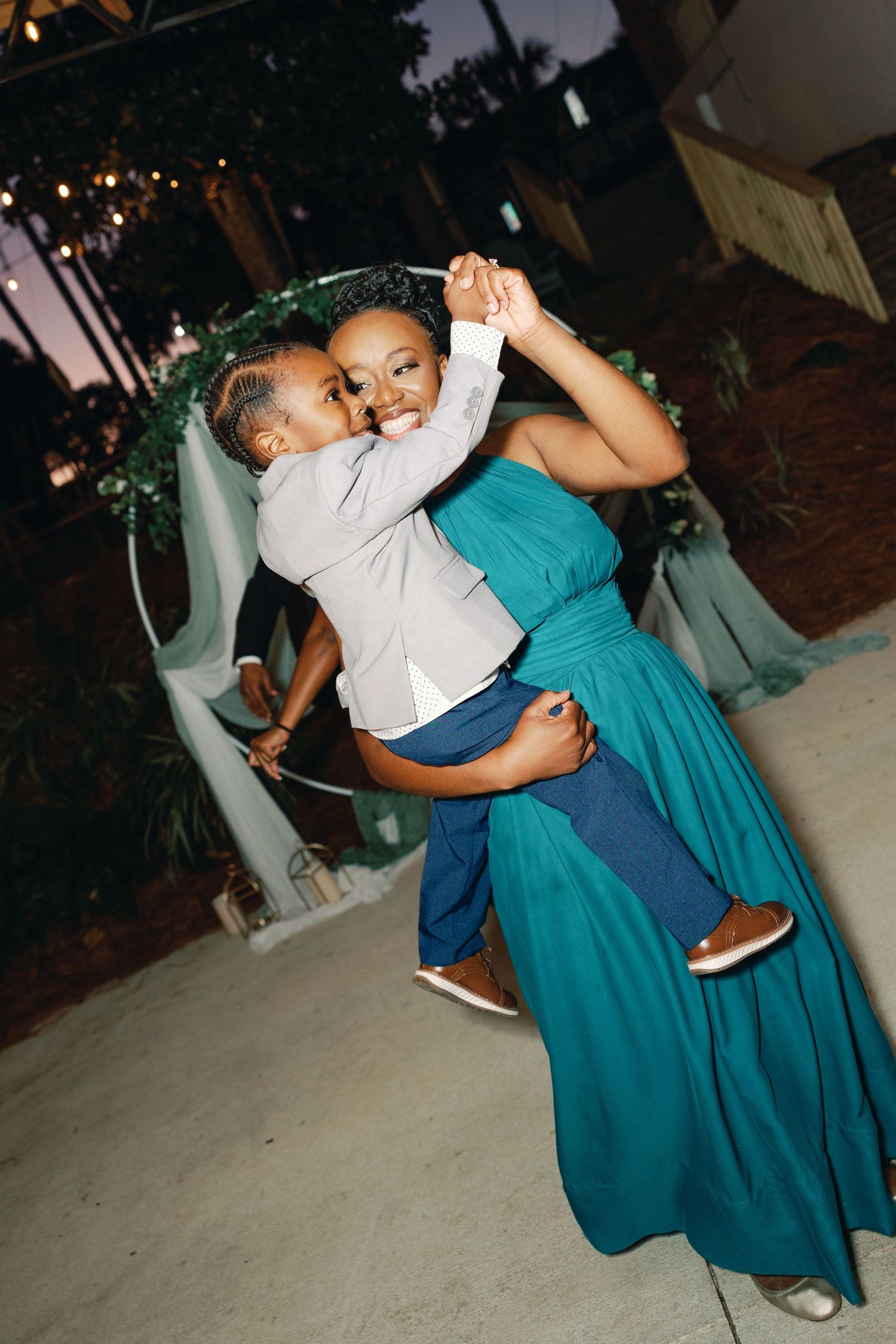 Two people dance together in an intimate pose at an evening event wearing turquoise and white outfits.
