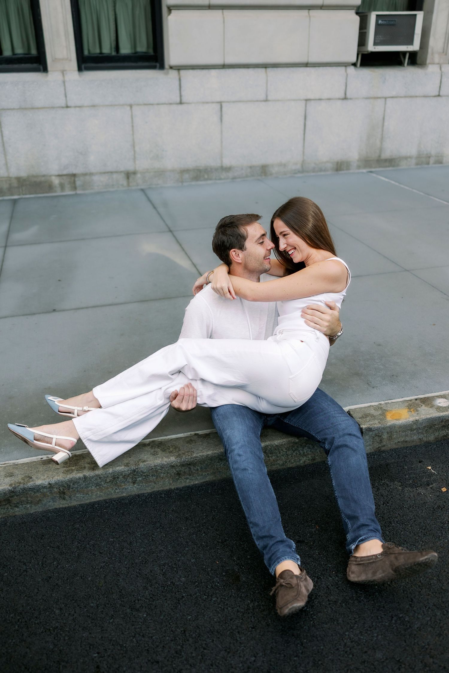 A couple in white and denim sits together on a curb in a progressive sequence of affectionate poses.