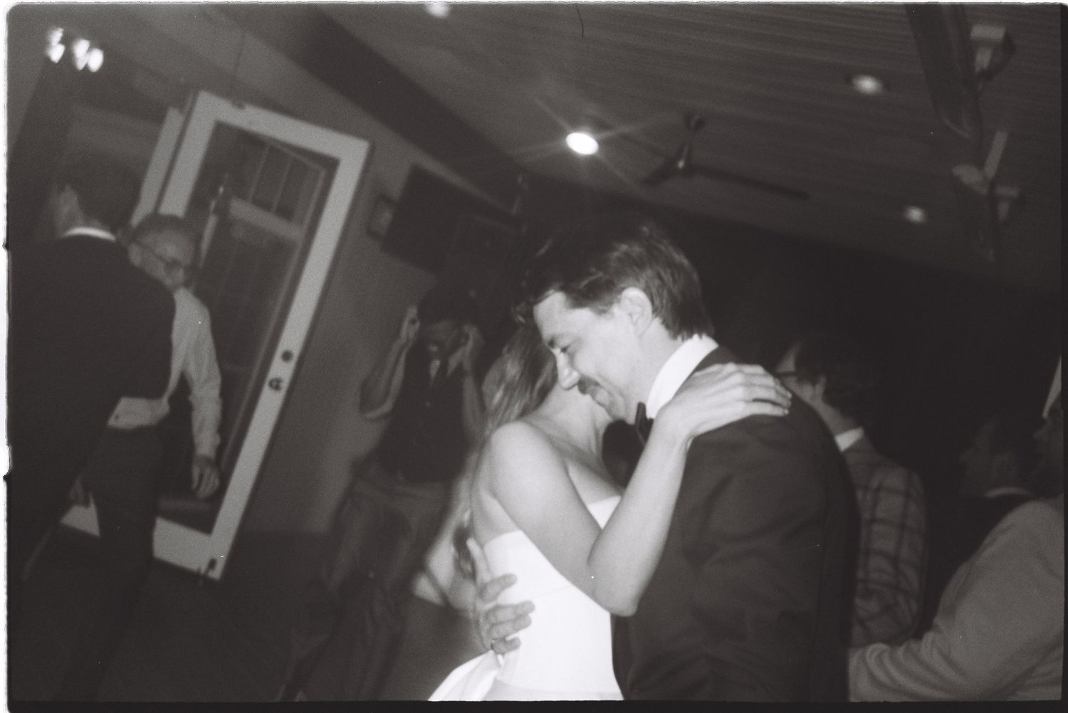 Black and white photo of a bride and groom sharing their first dance at a wedding reception.