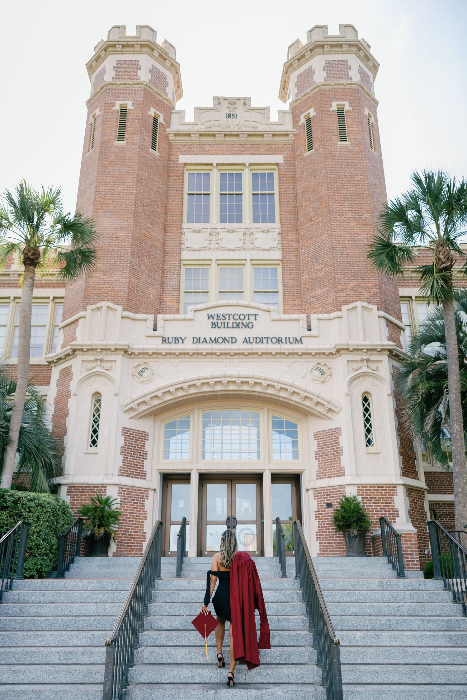 Woman in red cape ascending steps of Westcott Building Ruby Diamond Auditorium at Florida State University.