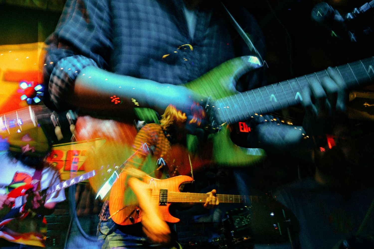 Colorful concert stage lights illuminate musical instruments and equipment during a live performance.