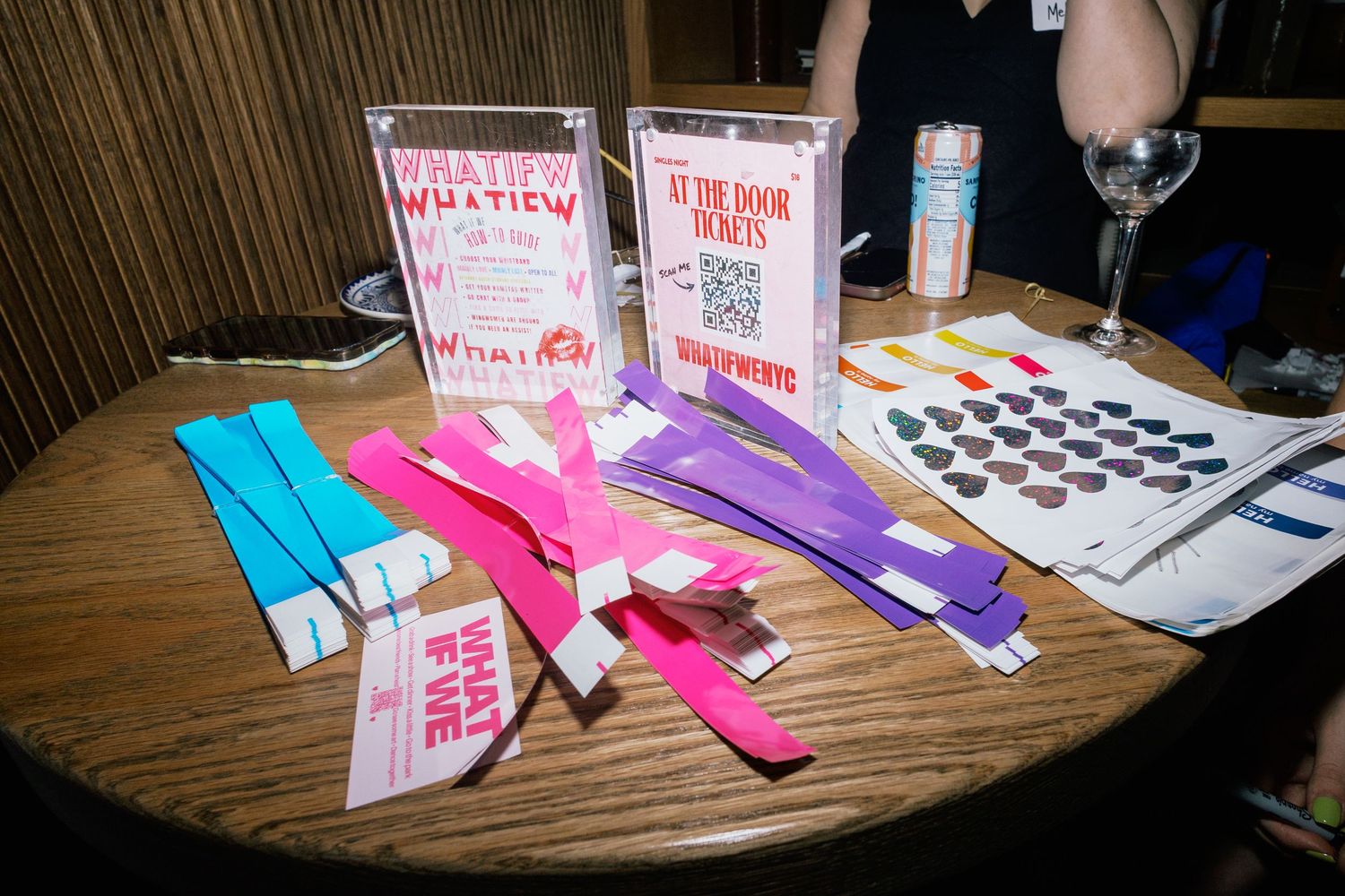 Colorful event wristbands and admission tickets displayed on a wooden table at a venue registration desk.