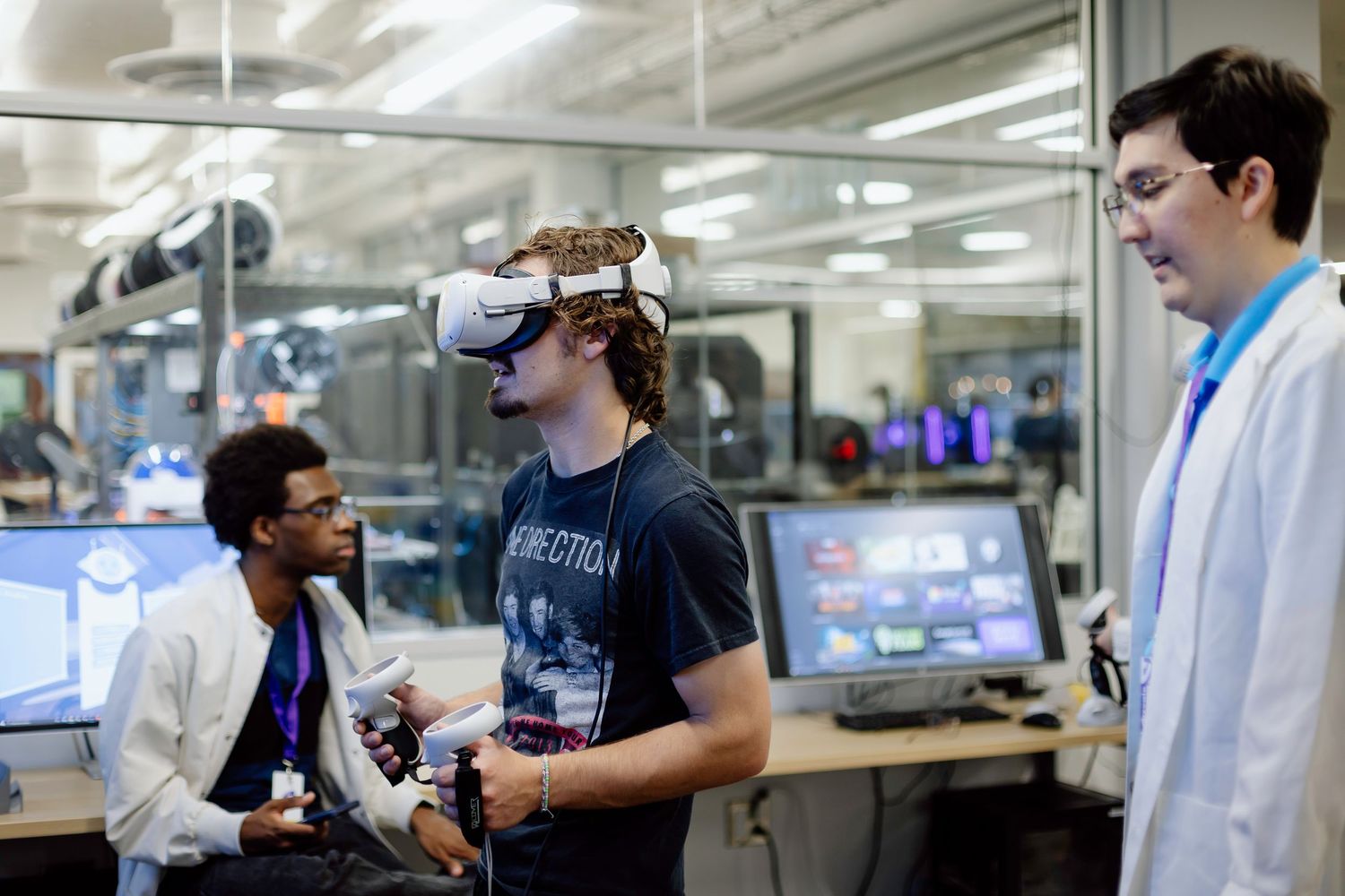 Students collaborate and test virtual reality equipment in a modern computer lab environment.