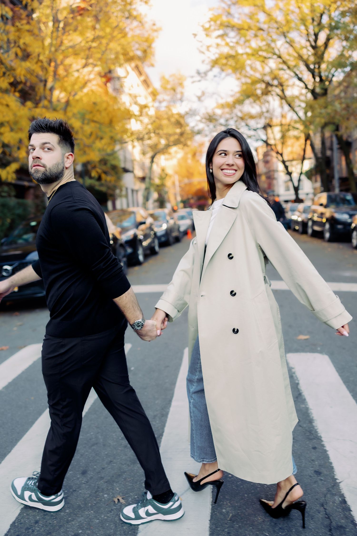 A playful sequence of dance moves between two people in autumn on a city street with golden trees in the background.