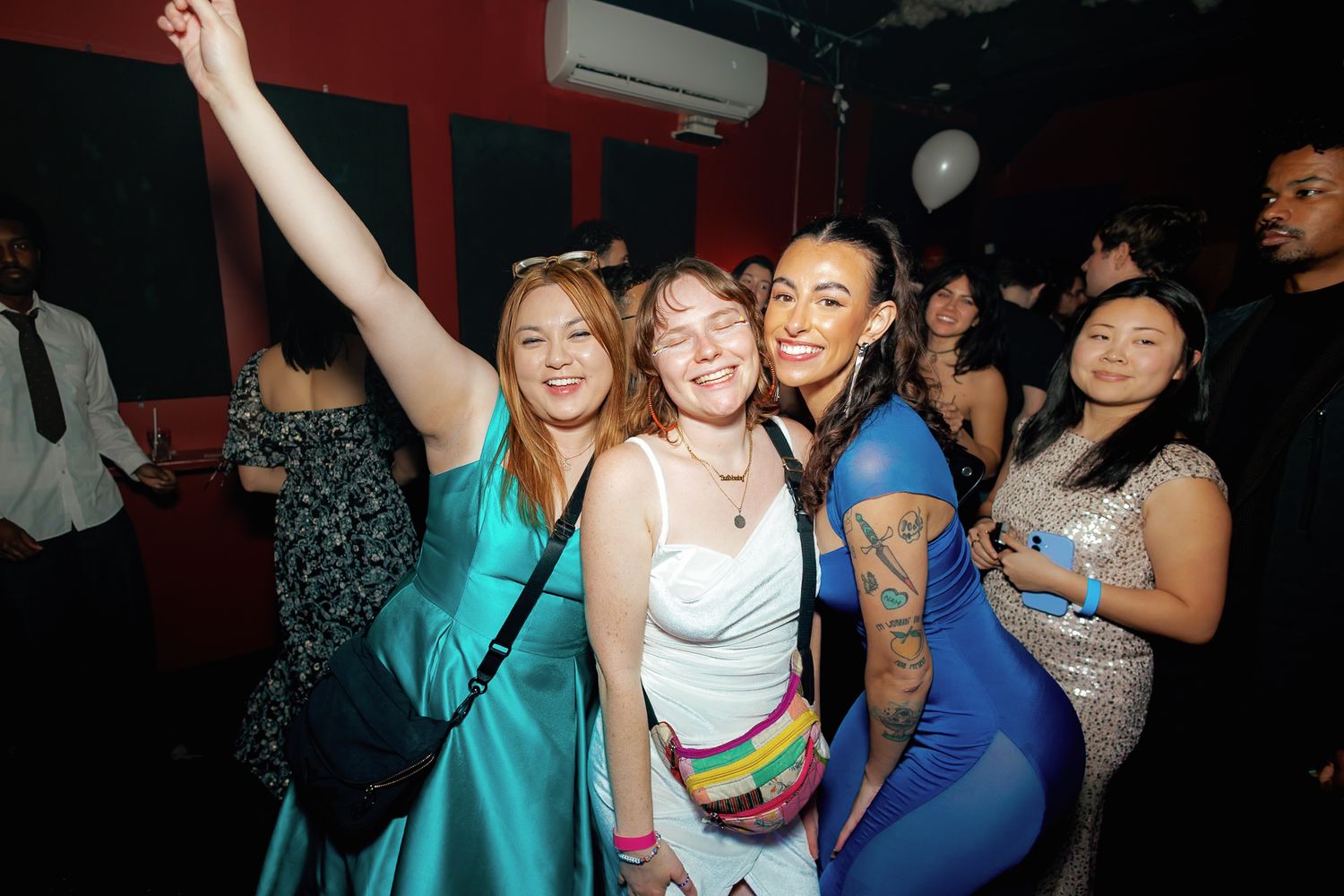 Group of women smiling and dancing together at a nightclub party event.