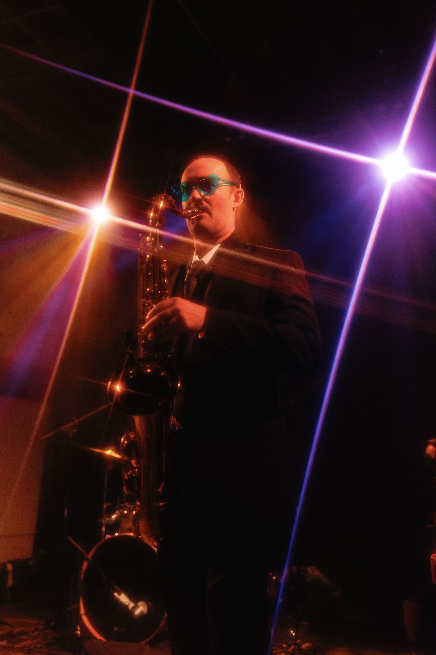 Saxophone player performing under colorful stage lights at a jazz concert.