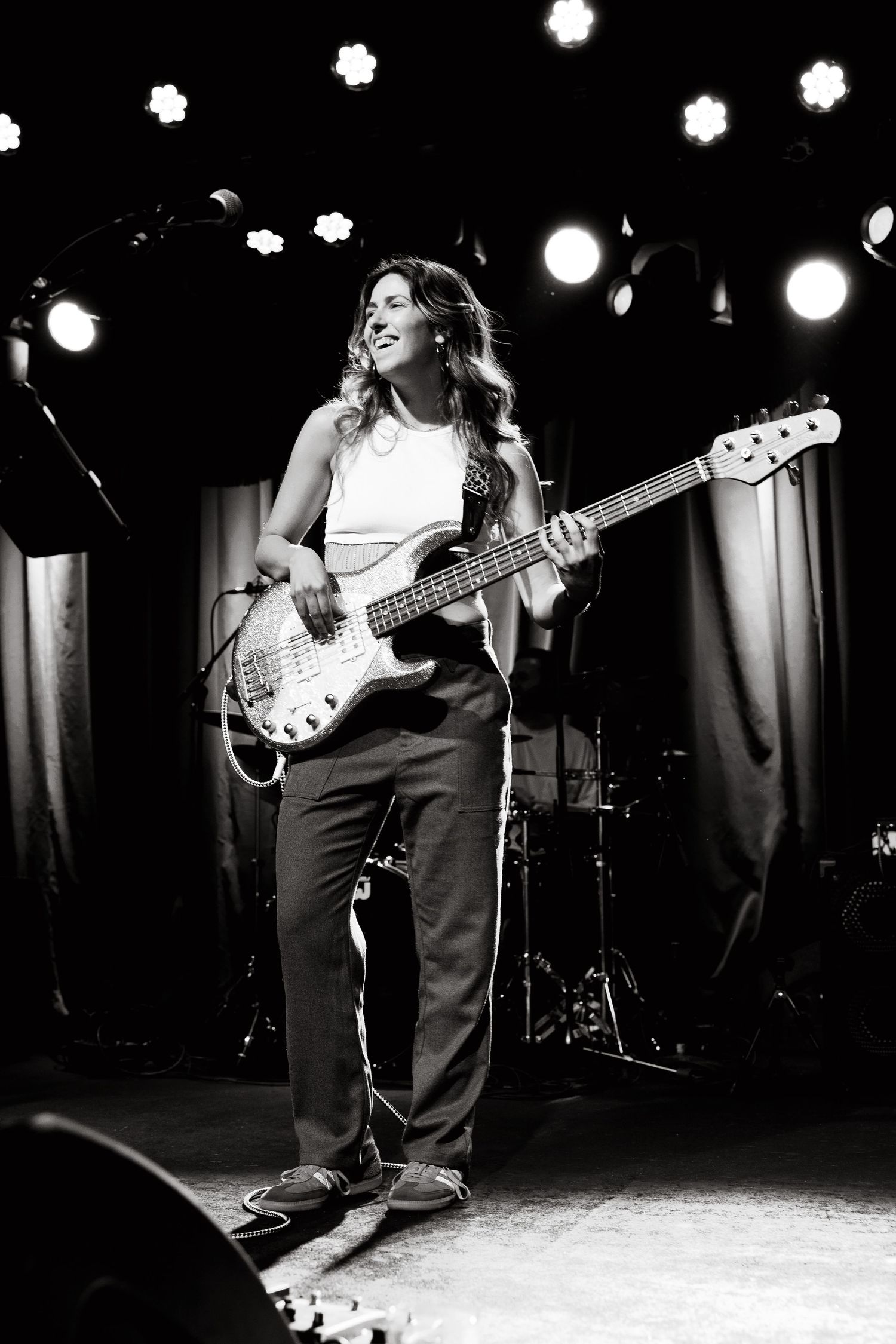 Black and white photo series of a musician performing with a bass guitar on stage under spotlights.