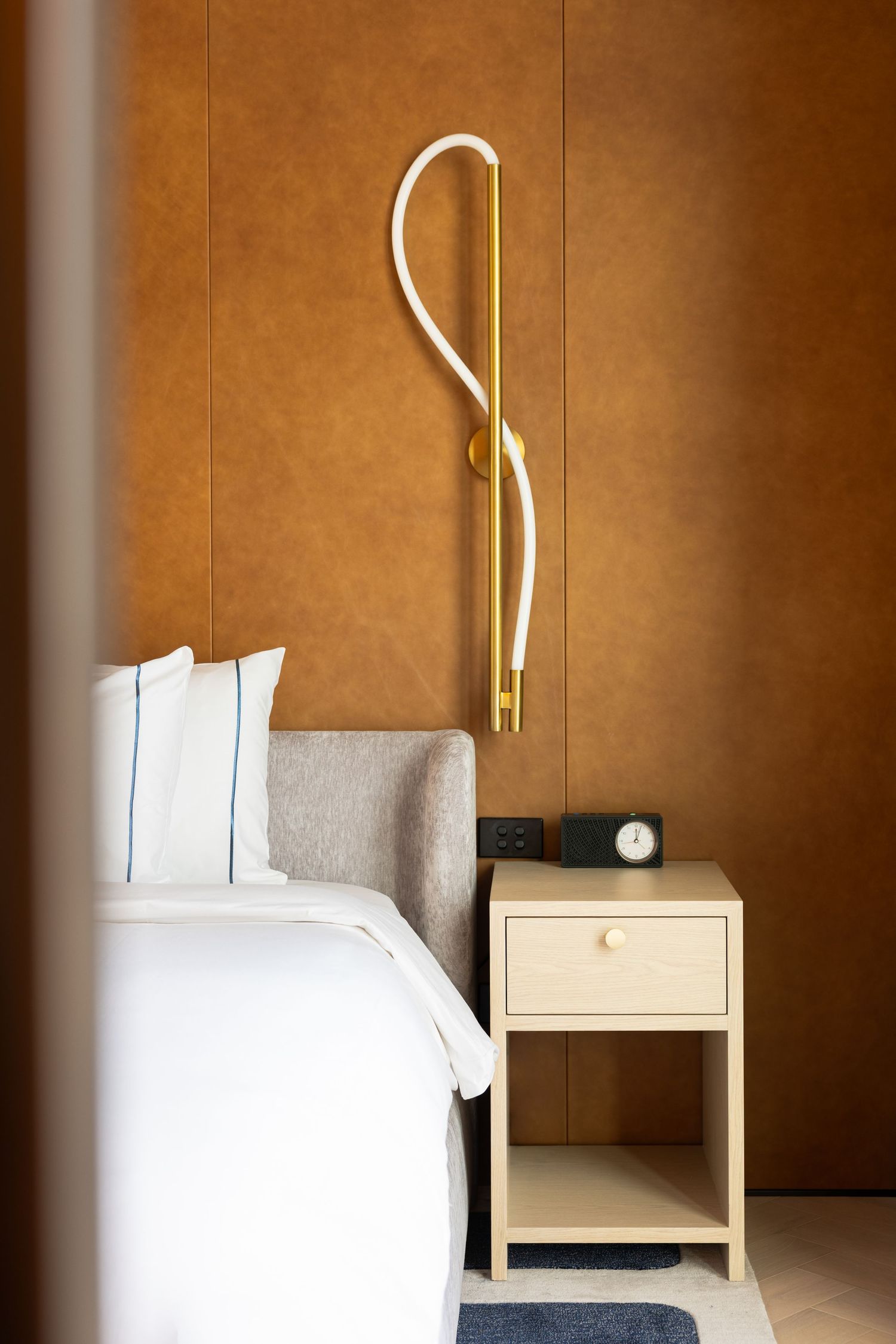 Leather bedhead and brass wall light in the penthouse at Lanson Place, Melbourne