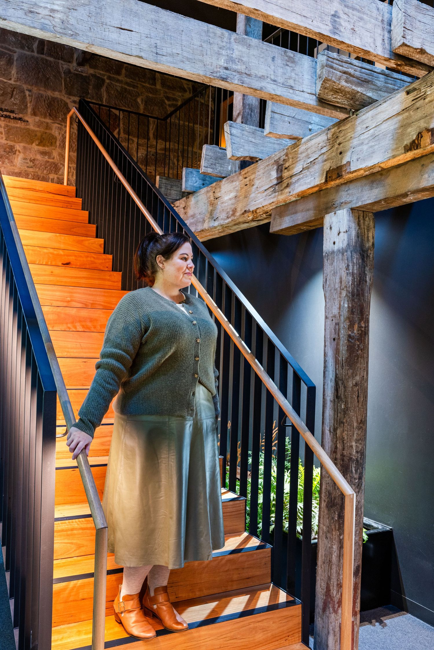 Woman in a Commonry knit and skirt on the timber staircase at MOSS Hotel