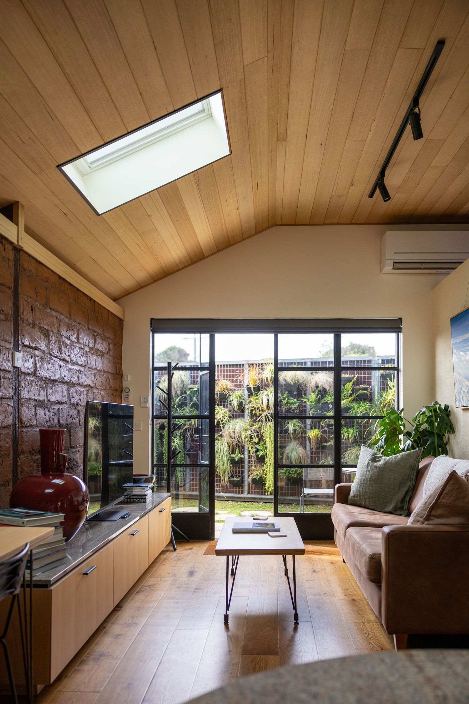 Living room with a leather sofa and garden views at Poets Corner Cottage, Phillip Island