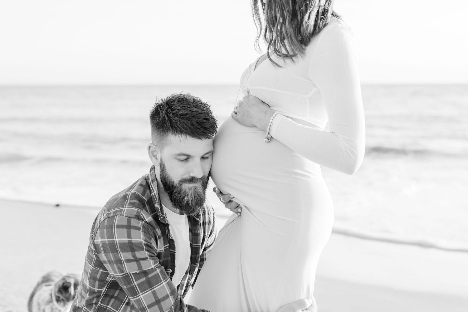 A couple shares an intimate moment during their beach maternity photoshoot.